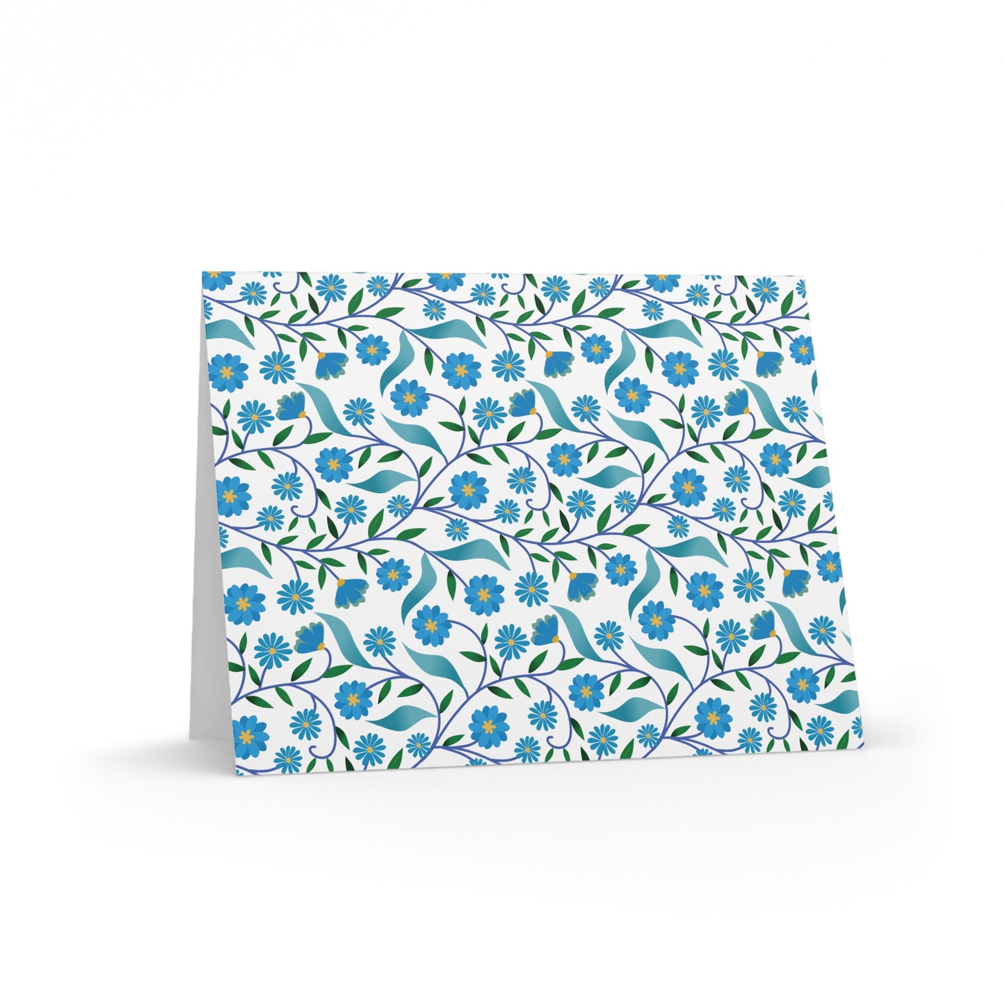 Floral Greeting Cards — Pack of 8/16/24 features a folded card with a vibrant floral pattern of small blue flowers and green leaves. Perfect for heartfelt messages, complete with a matching white envelope.