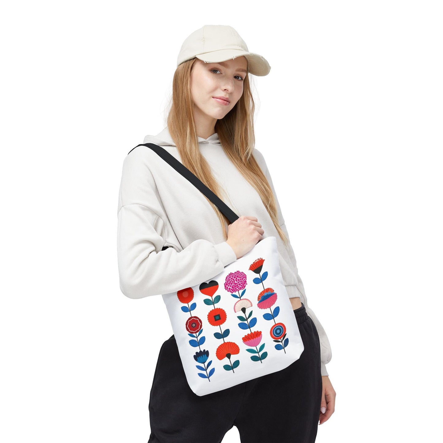 Woman wearing a hat holds a Floral Pattern Tote Bag with a vibrant flower design, embodying FireBrook Essentials' blend of style and functionality.