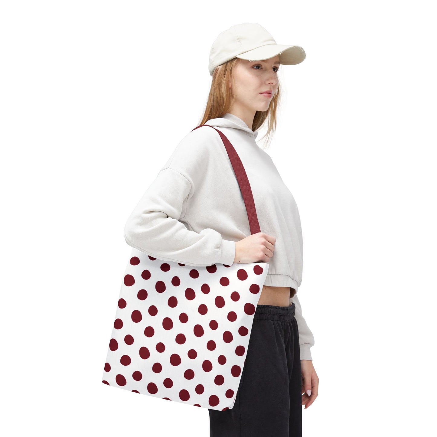 Burgundy Polka Dots Tote Bag held by a woman in white attire, showcasing its stylish design with a red and white polka dot pattern, perfect for adding a pop of color to daily essentials.