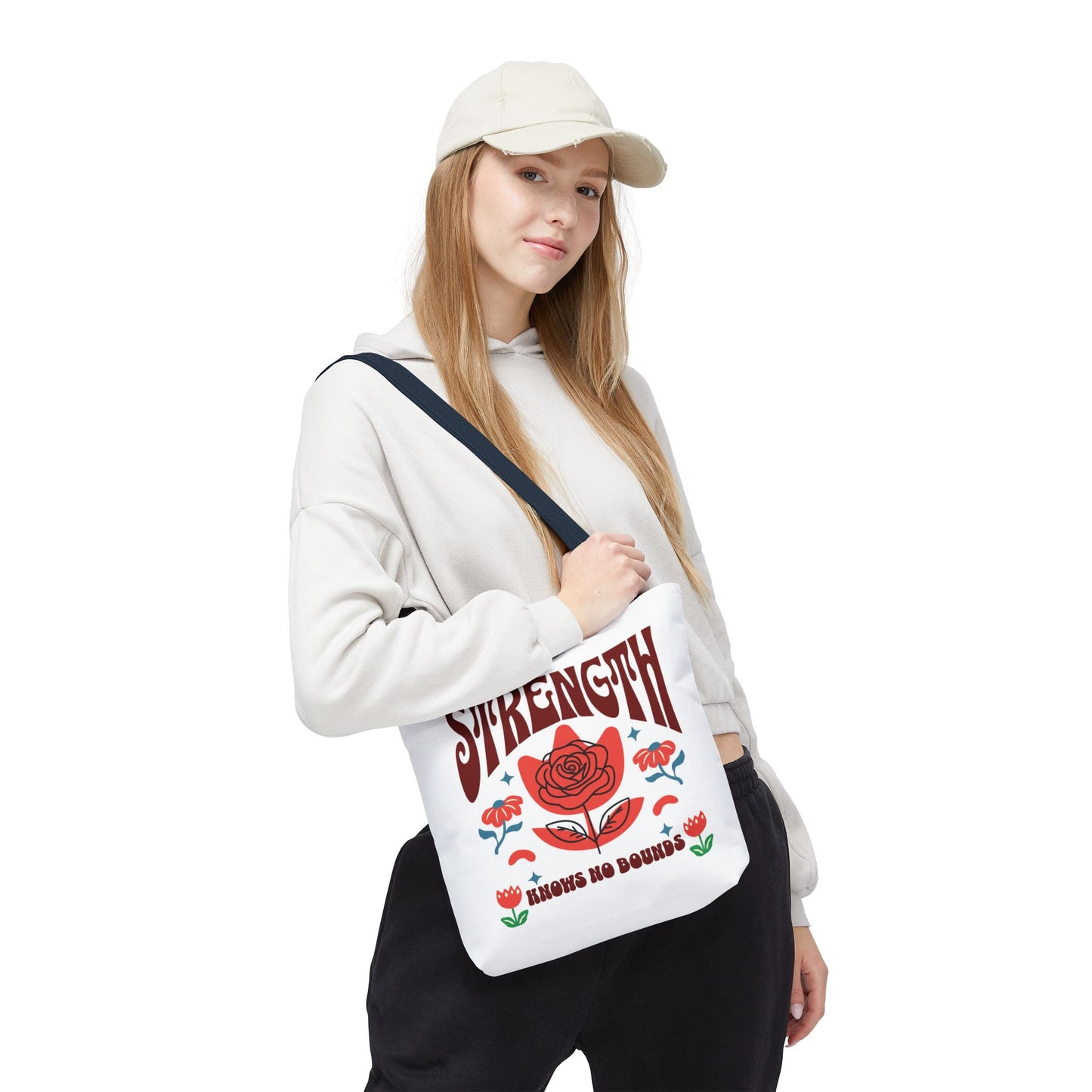Woman holding the Strength Knows No Bounds Tote Bag, showcasing its stylish design with a red flower. Ideal for everyday use, embodying resilience and durability.
