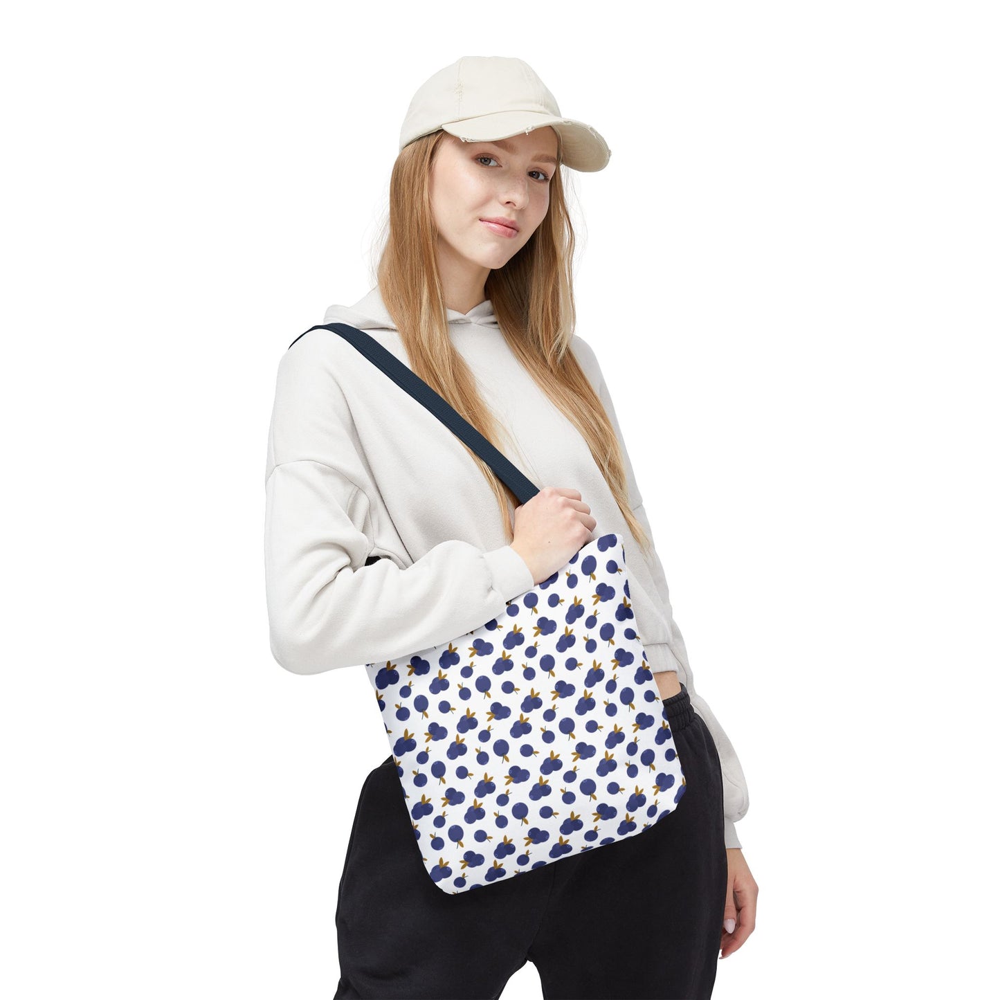 Blueberry Tote Bag held in hand, showcasing its charming blueberry pattern and durable 100% polyester fabric. Ideal for carrying essentials, it features reinforced handles and boxed corners for practicality and style.