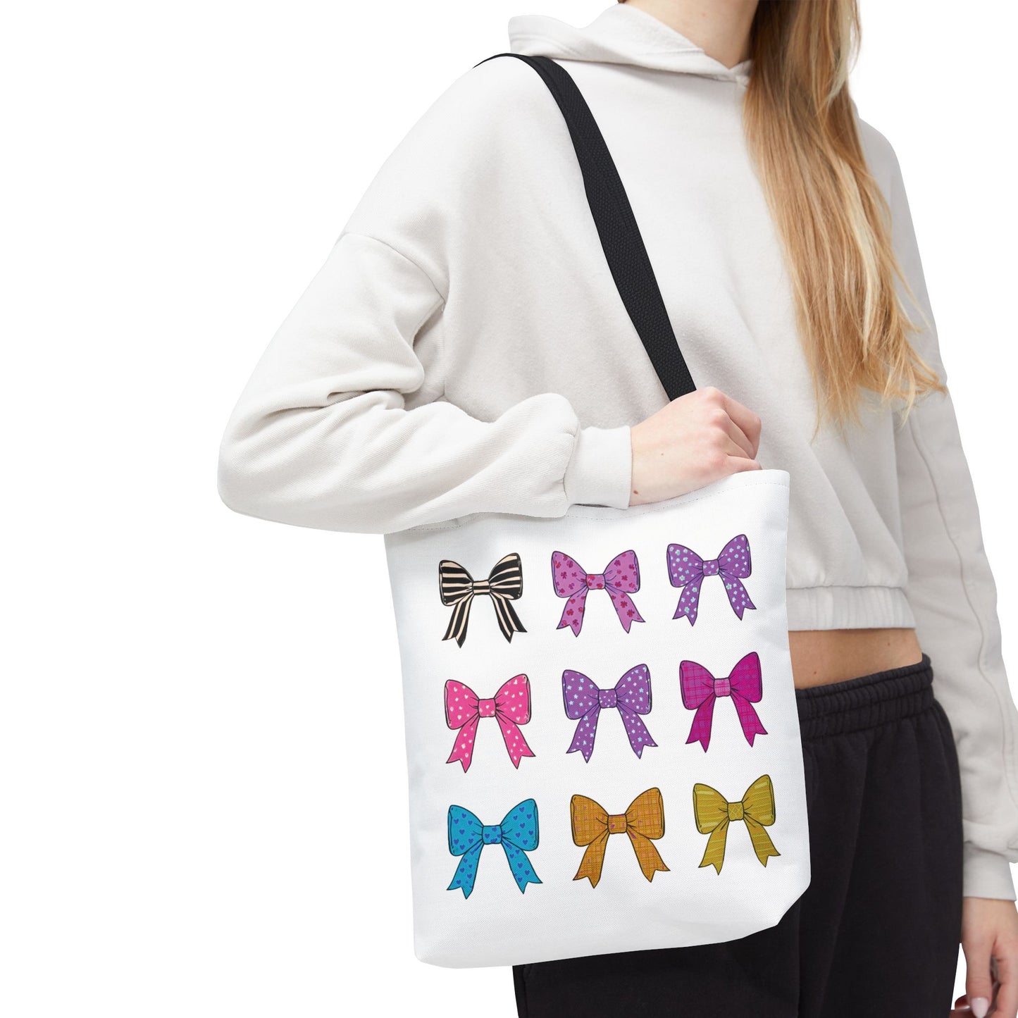 Woman holding the Bows Ribbons Tote Bag, adorned with multiple bow prints, showcasing its stylish design and spacious, durable build for daily adventures.