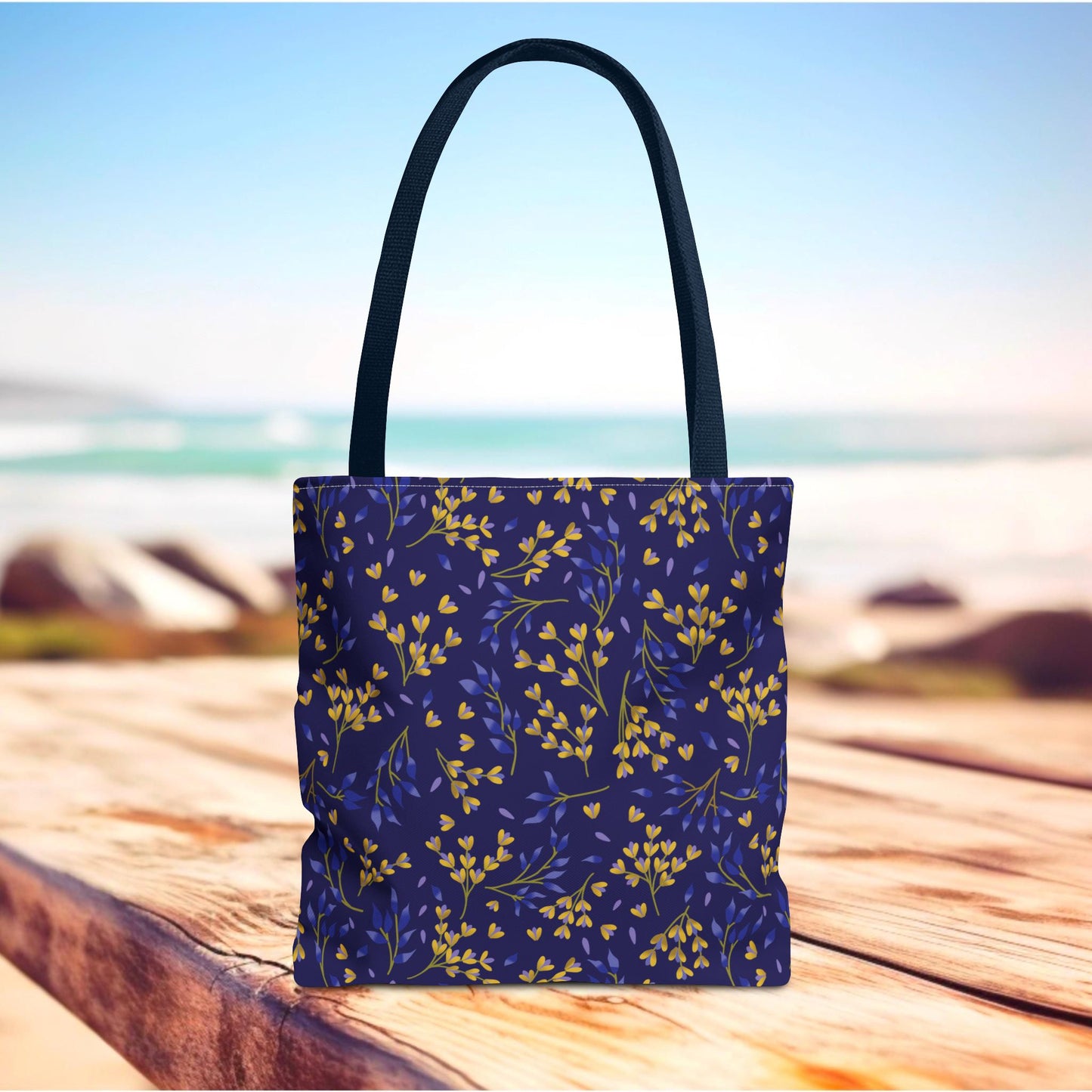 Floral Tote Bag with a navy backdrop showcases yellow and muted-blue leafy sprigs, perfect for joyful outings. Sturdy and stylish, it embodies FireBrook Designs' commitment to uplifting, practical accessories.