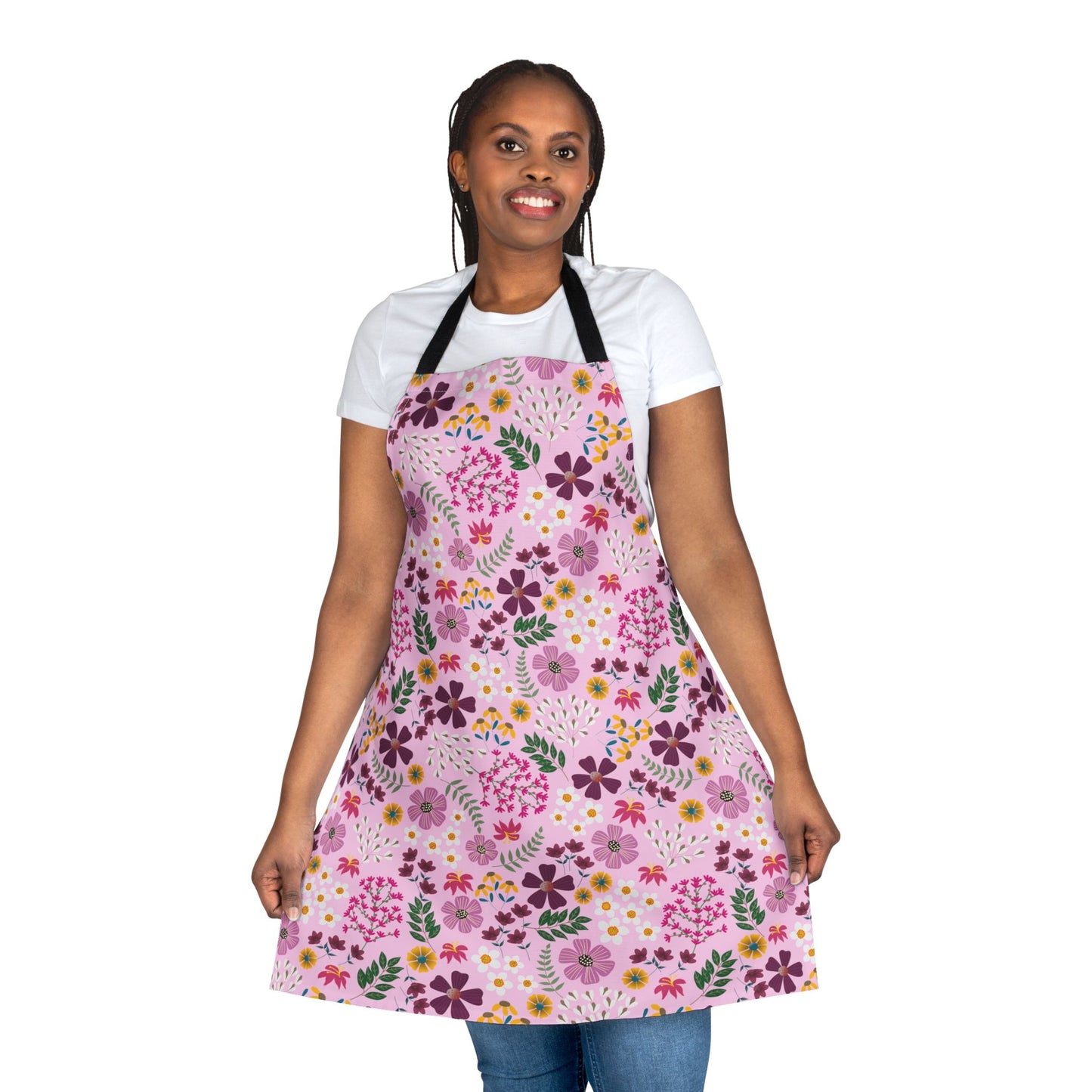 Floral Apron: A person smiles, wearing a vibrant floral-patterned apron over a white T-shirt and blue jeans. This stylish, stain-free apron from FireBrook Designs offers comfort and joy with its soft polyester canvas.