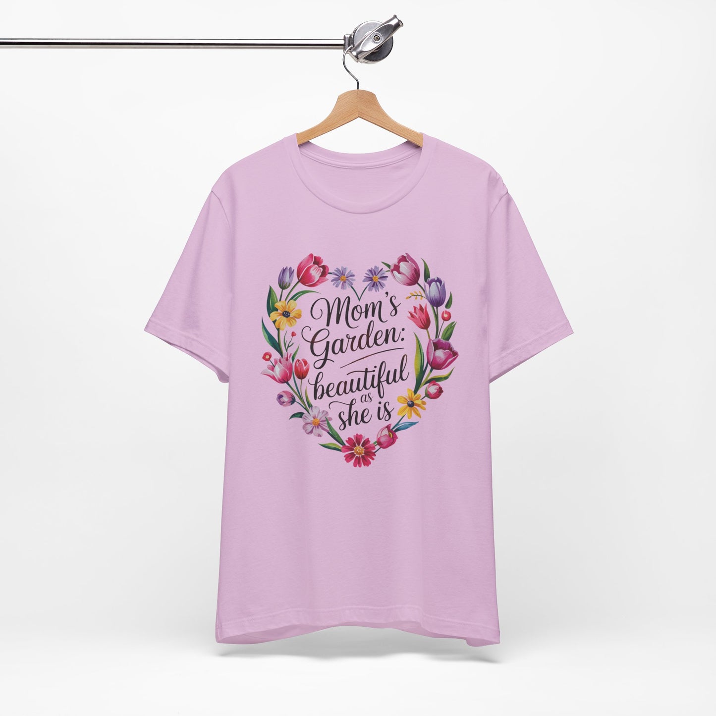 Mom's Garden is as Beautiful as She Is Mother's Day Comfort Colors Unisex T-Shirt, featuring a heart-shaped floral design with black text, hanging on a wooden swinger.