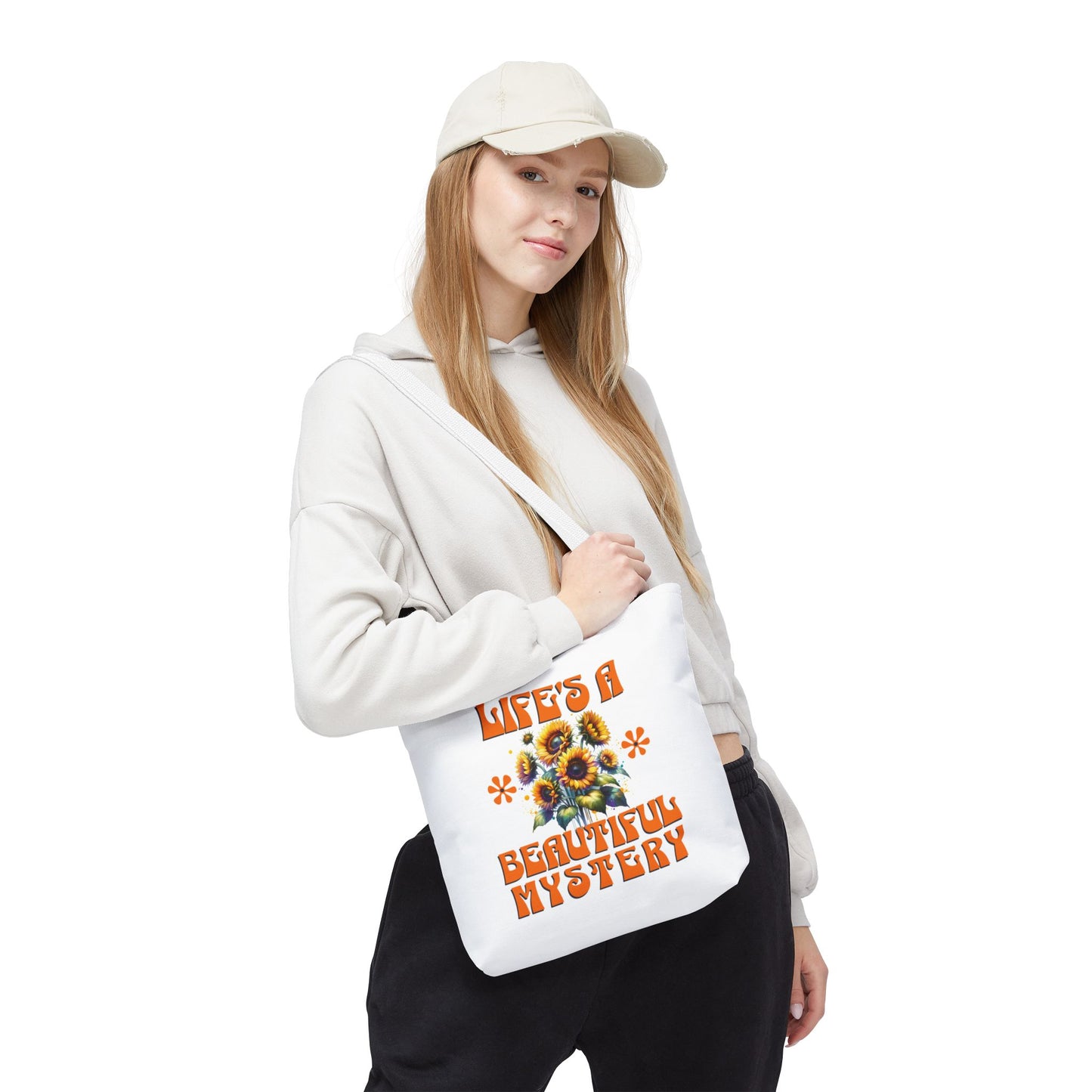 Woman in a white sweatshirt holds the Life's A Beautiful Mystery Tote Bag, showcasing its floral design and sturdy handles, embodying exploration and intrigue.