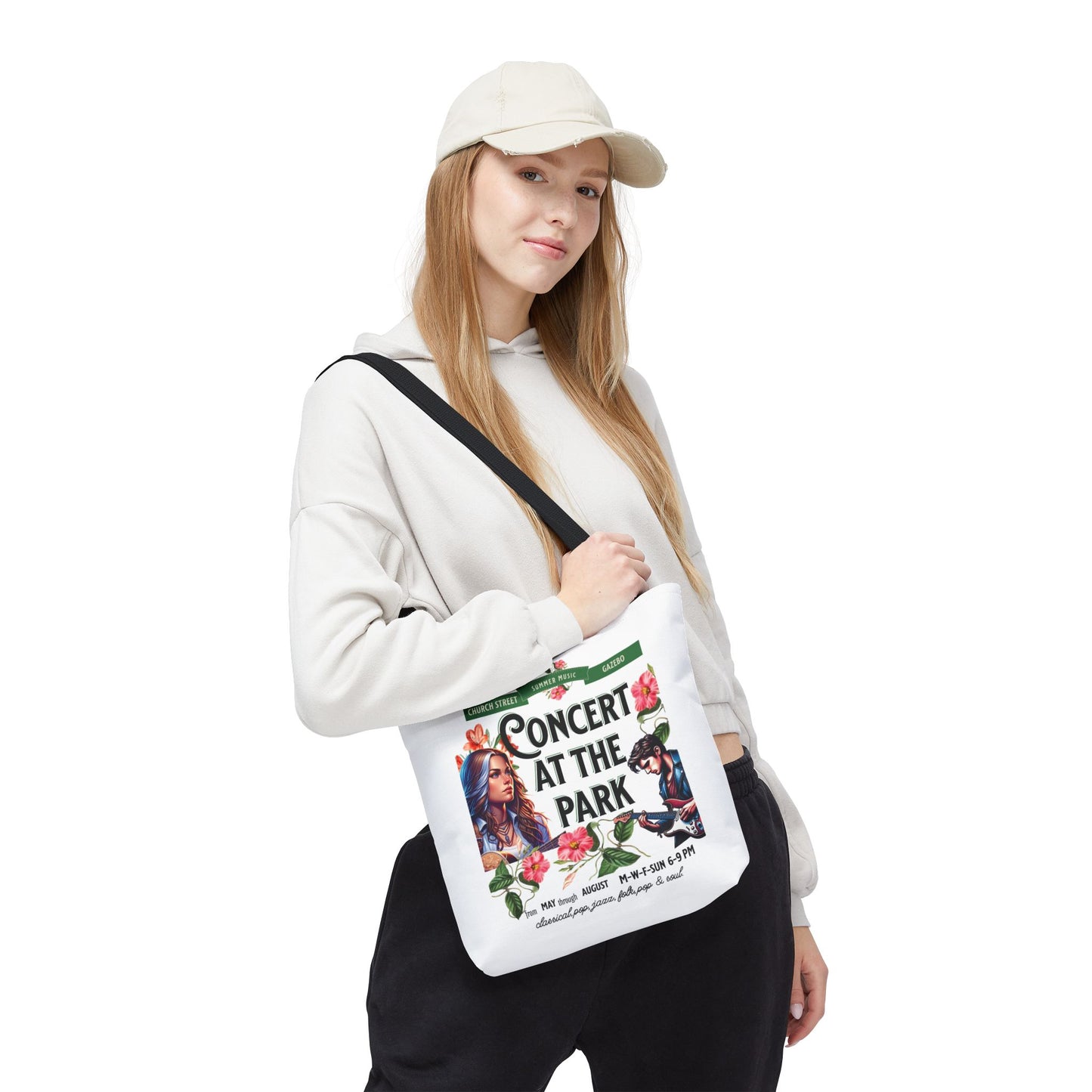 A woman in a white hat holds the Concert At the Park Tote Bag, featuring a lively concert design, ideal for music lovers and outdoor enthusiasts.