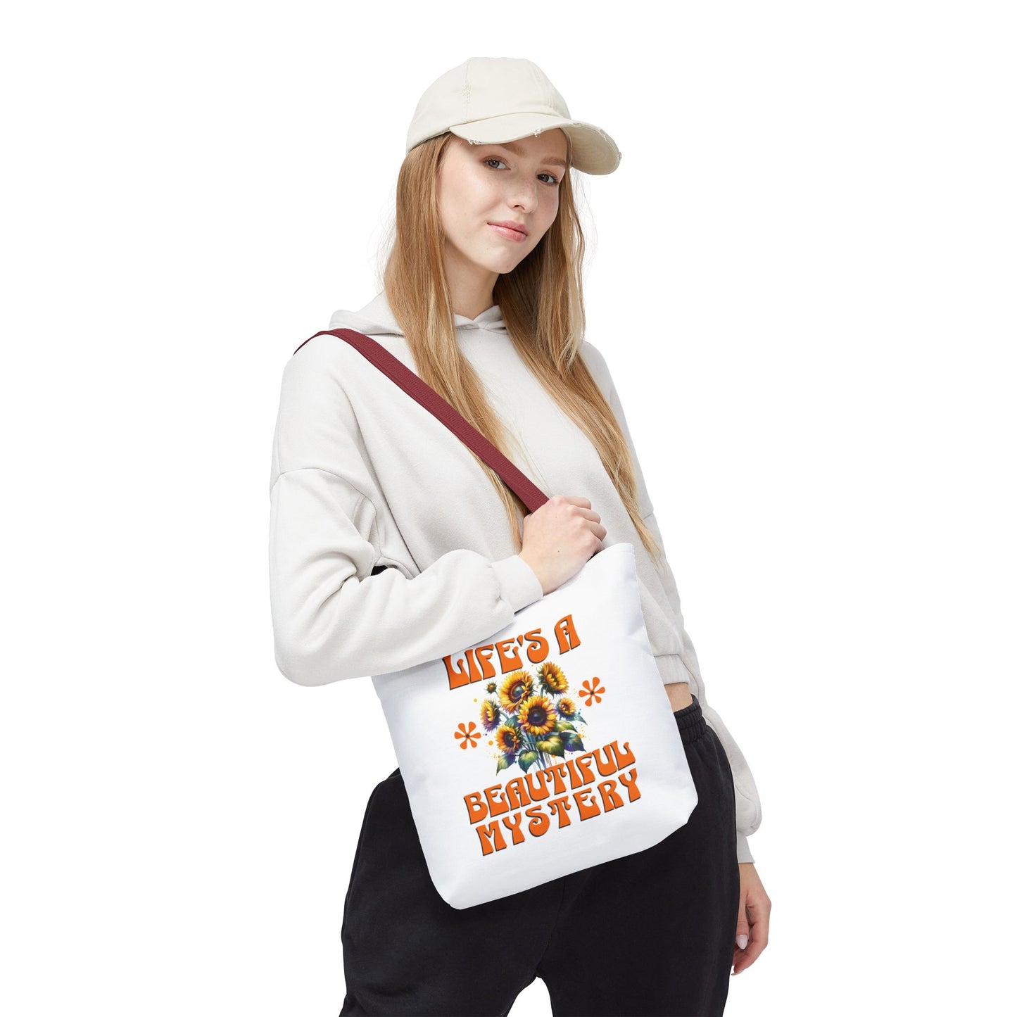 Woman in a white sweatshirt holding the Life's A Beautiful Mystery Tote Bag with a flower design, embodying intrigue and joy for daily adventures.