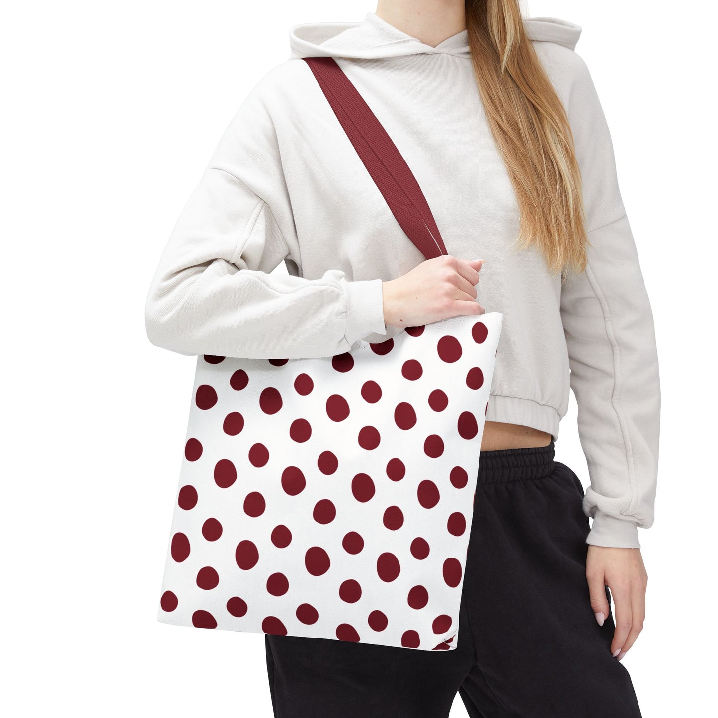 Burgundy Polka Dots Tote Bag: A woman holds a red and white polka dot tote bag, showcasing its durable polyester fabric and reinforced handles, perfect for stylish, everyday use.