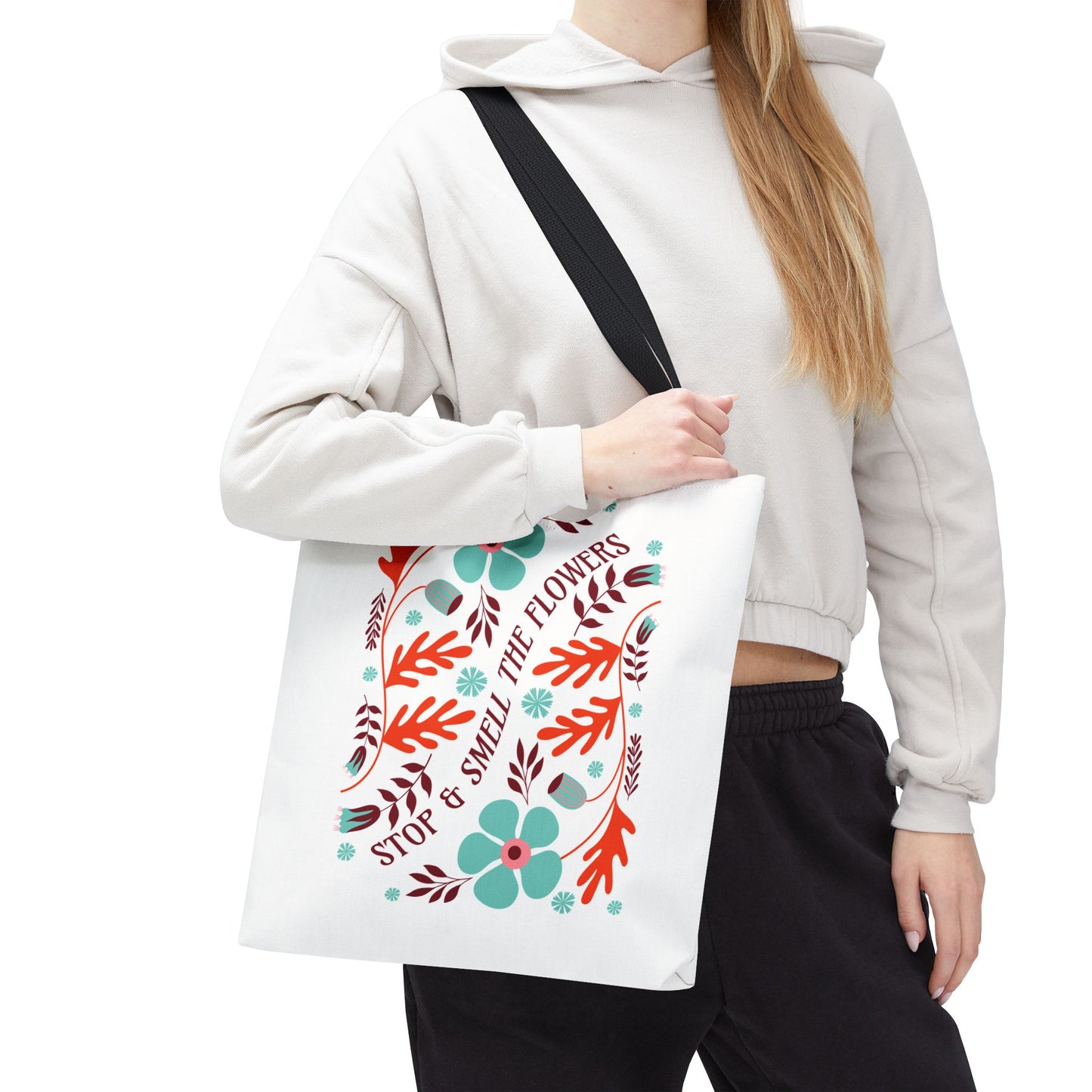 A woman holding the Stop and Smell The Flowers Tote Bag, featuring a floral design, ideal for carrying essentials and spreading positivity.