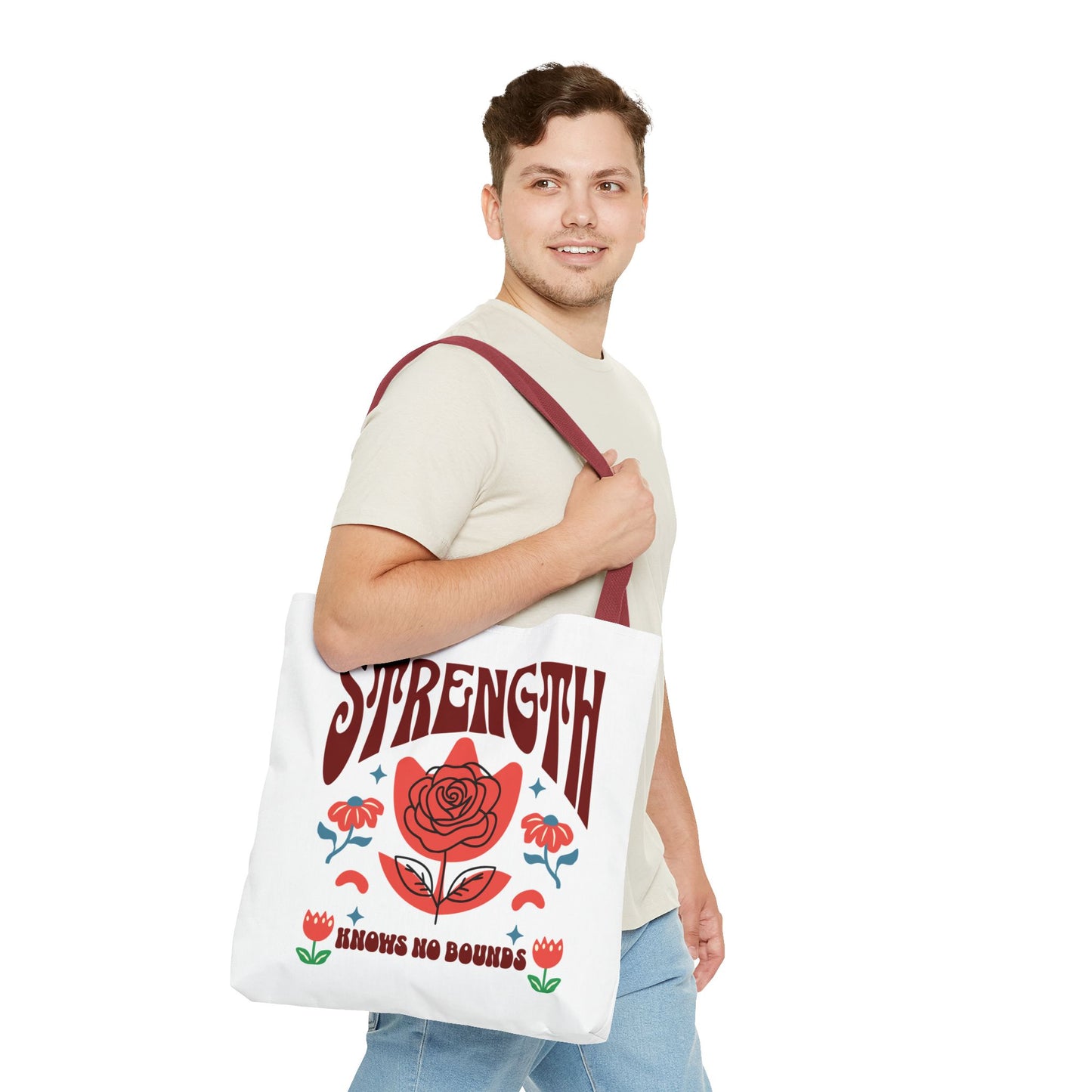 Man holding the Strength Knows No Bounds Tote Bag, featuring a red flower and motivational quote. Designed for strength and style, ideal for everyday use.
