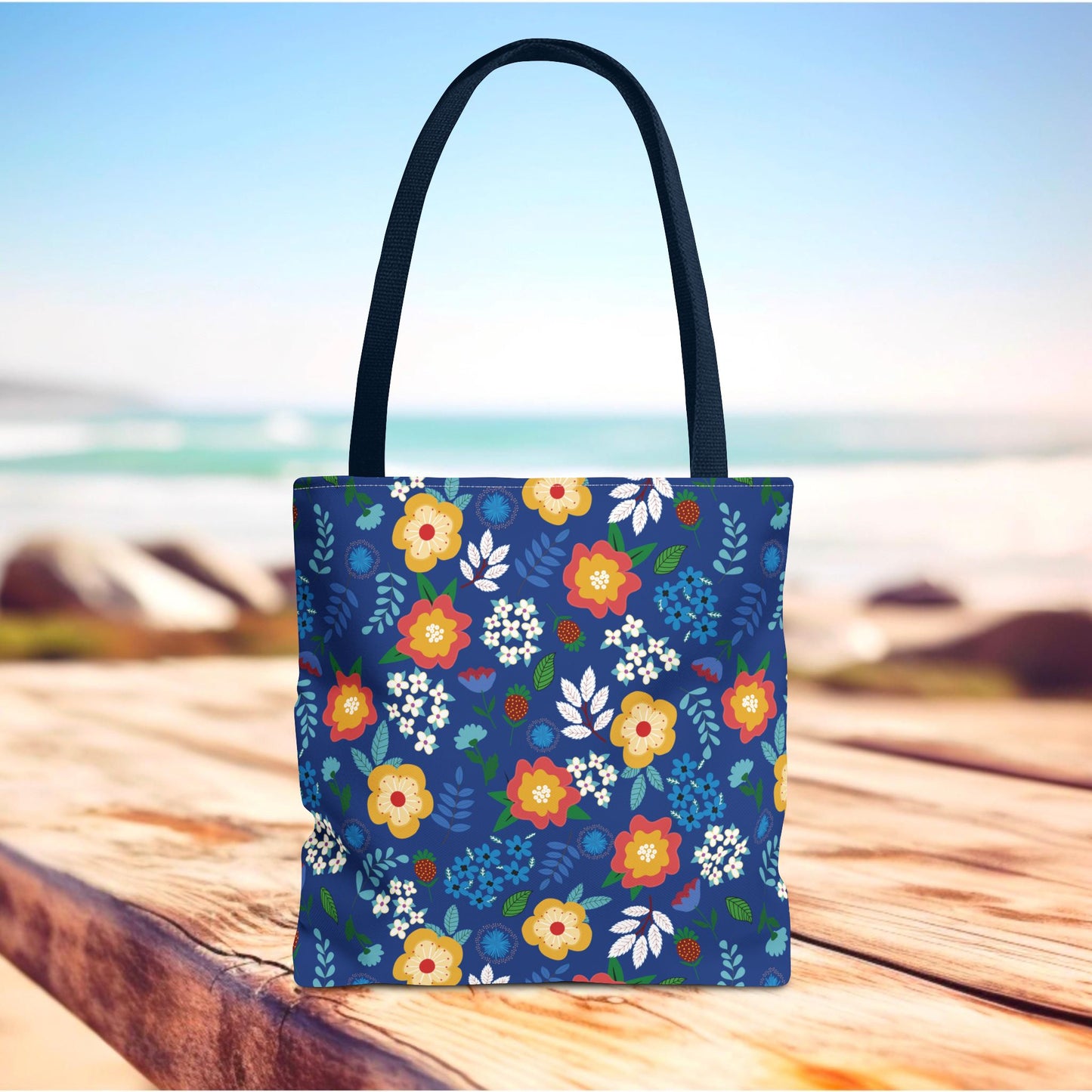 Floral Tote Bag with vibrant floral pattern sits on a wooden surface, featuring durable black straps. Perfect for summer outings.