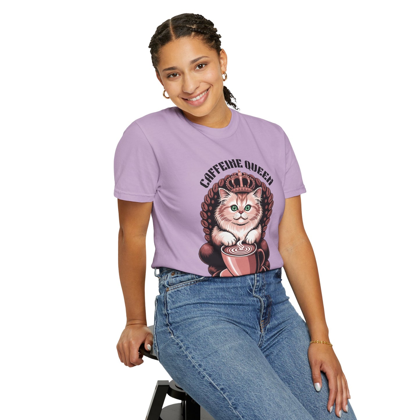 Cat Caffeine Queen T-shirt featuring a cat with a crown and coffee, worn by a smiling woman sitting on a stool, showcasing casual comfort and playful style.