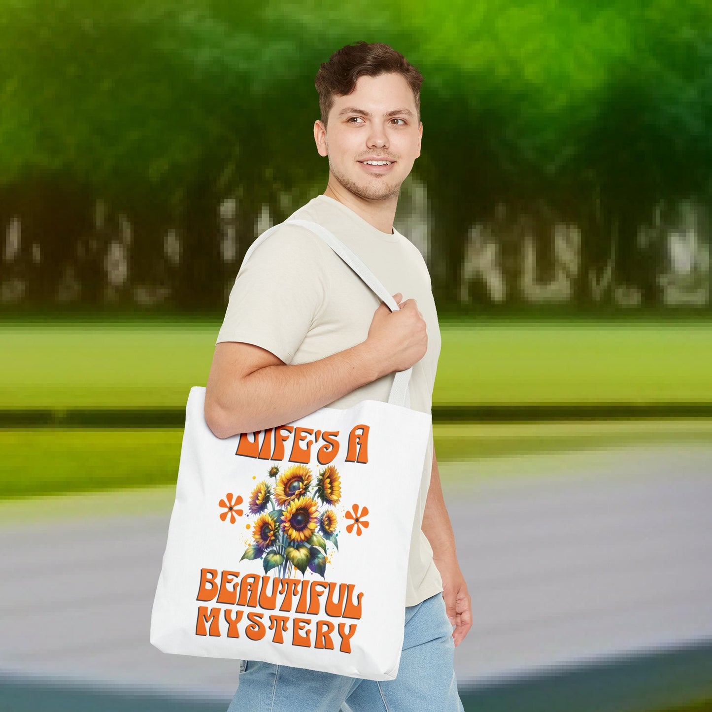 Man smiling while holding the Life's A Beautiful Mystery Tote Bag, featuring a sunflower design, conveying intrigue and joy for life's adventures.