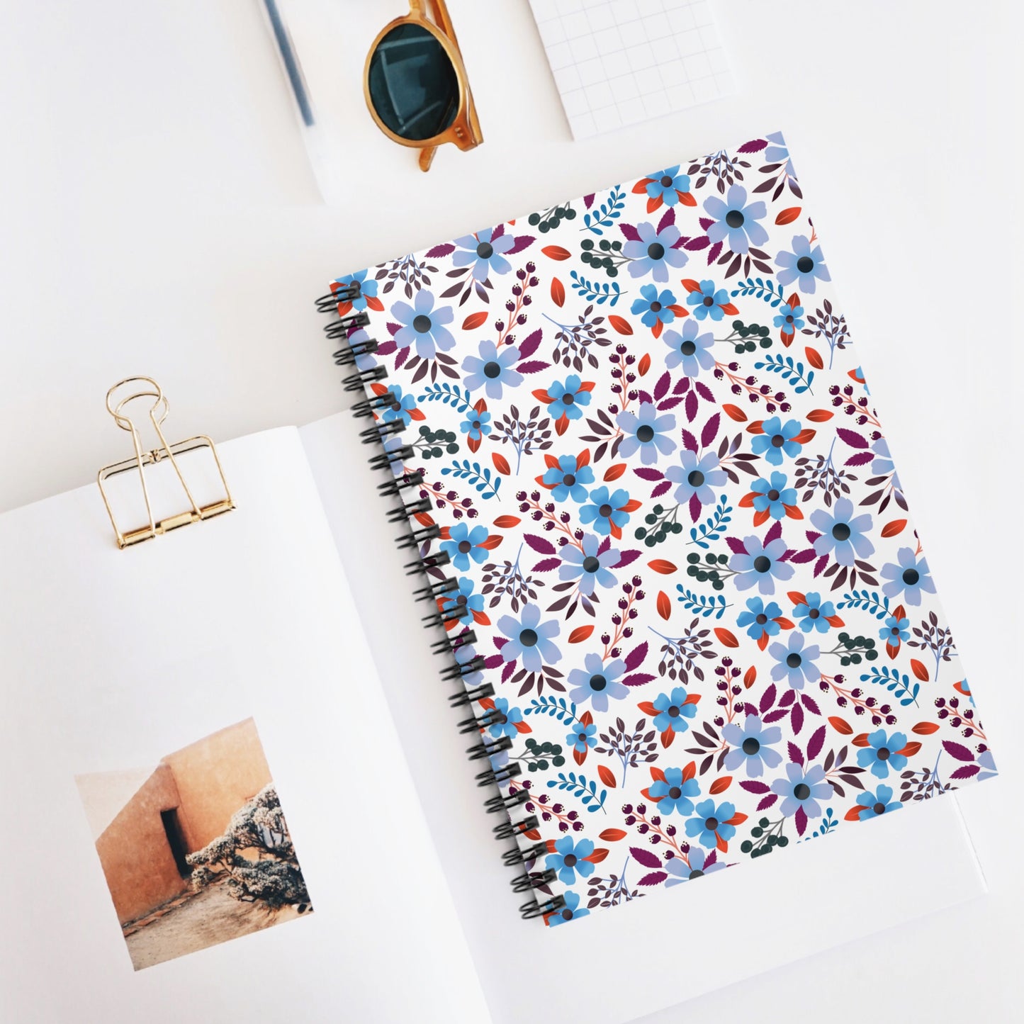 SPIRAL NOTEBOOK, DURABLE COVER, RULED, 6X8 – BLOOM BRIGHTLY features a floral-patterned cover, perfect for vibrant note-taking. Styled with a gold binder clip and sunglasses, it embodies FireBrook Essentials' joyful, practical design ethos.