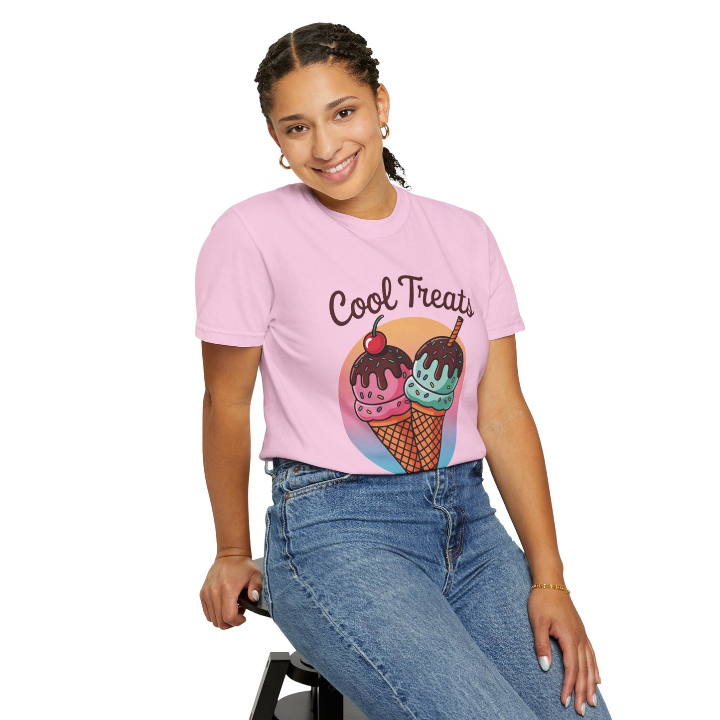A woman in a pink shirt and blue jeans, sitting on a stool and smiling, showcases the Ice Cream Cool Treats Comfort Colors Unisex T-Shirt, embodying FireBrook Essentials' joyful and stylish apparel.
