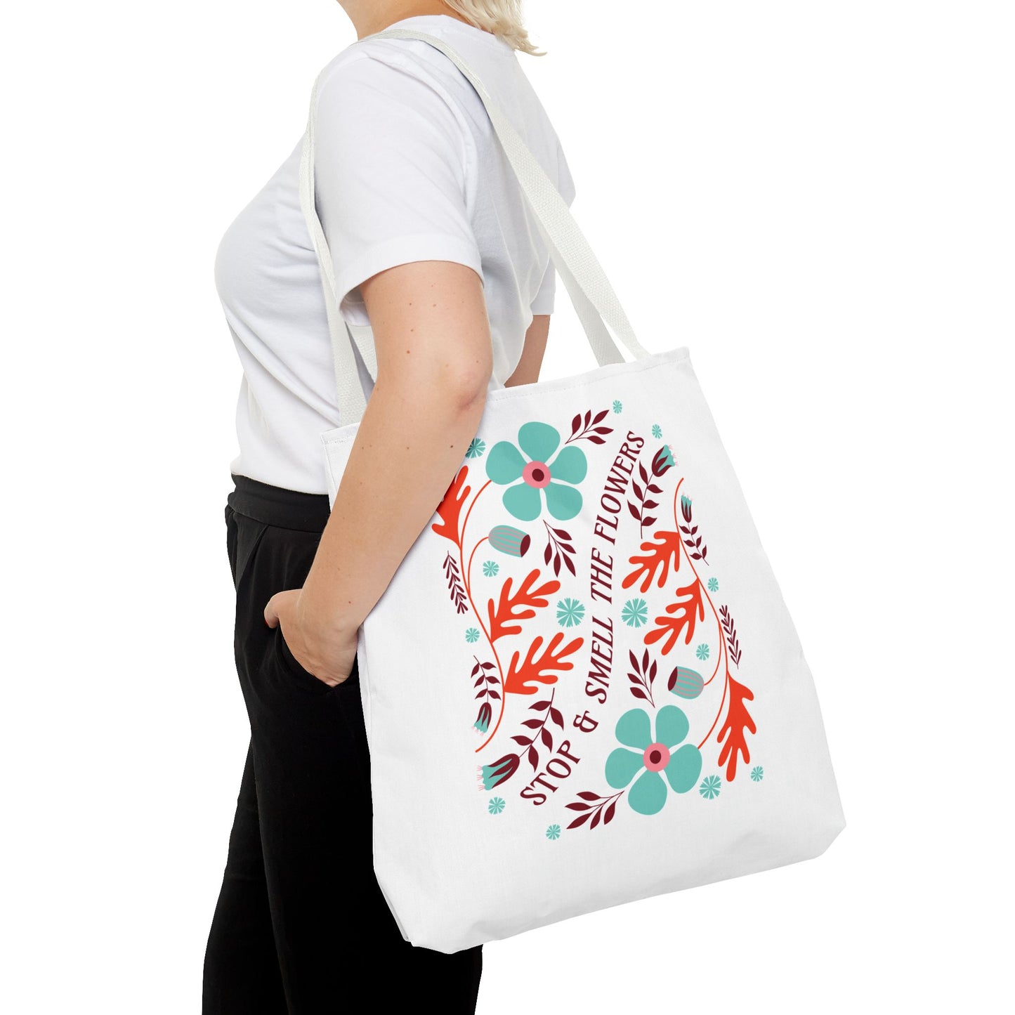 Woman holding the Stop and Smell The Flowers Tote Bag, showcasing its floral design, ideal for carrying essentials while promoting positivity and nature-inspired beauty.