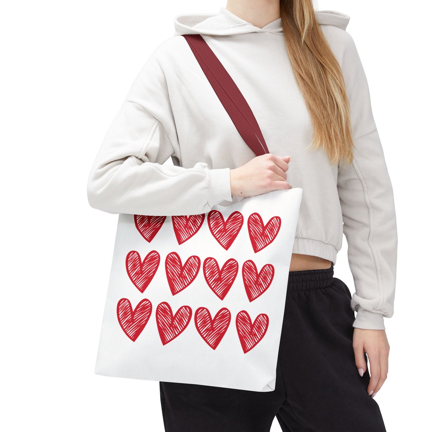 Hearts Tote Bag: A woman holds a white tote adorned with red hearts, showcasing its playful and charming design, perfect for everyday use and special occasions.