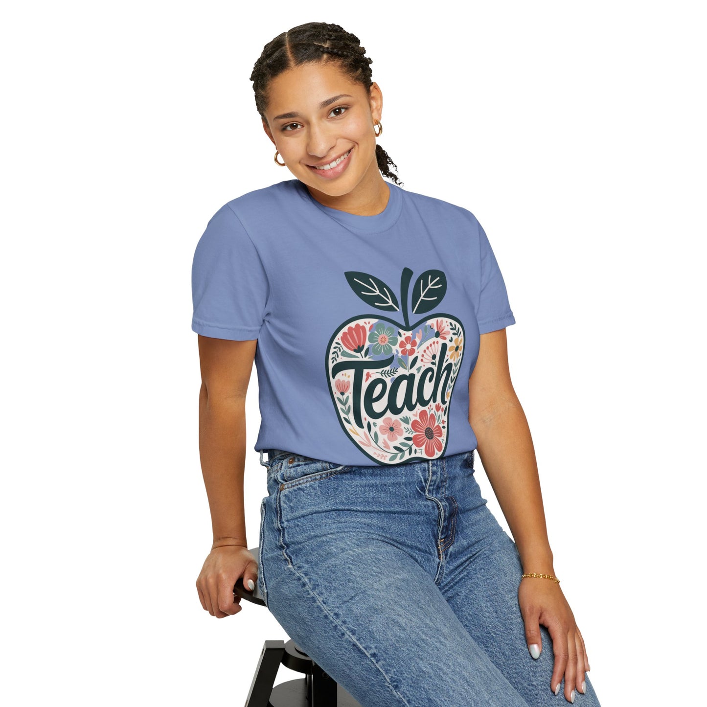 Floral Apple TEACH T-shirt features a whimsical apple filled with pastel floral designs, overlaid by TEACH in textured script, offering a cozy, artistic vibe ideal for educators.