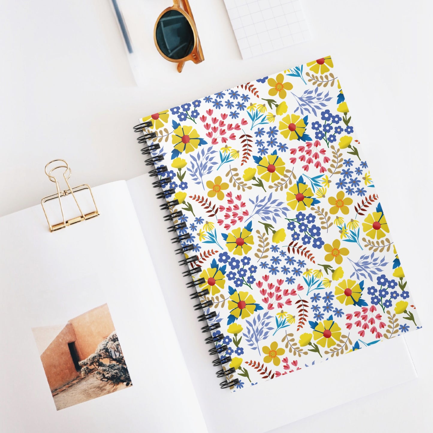 Spiral Notebook, Durable Cover, Ruled, 6x8 with a vibrant, multicolored floral cover, centered in a neatly arranged desktop flat-lay, perfect for stylish and eco-friendly note-taking with FireBrook Essentials.