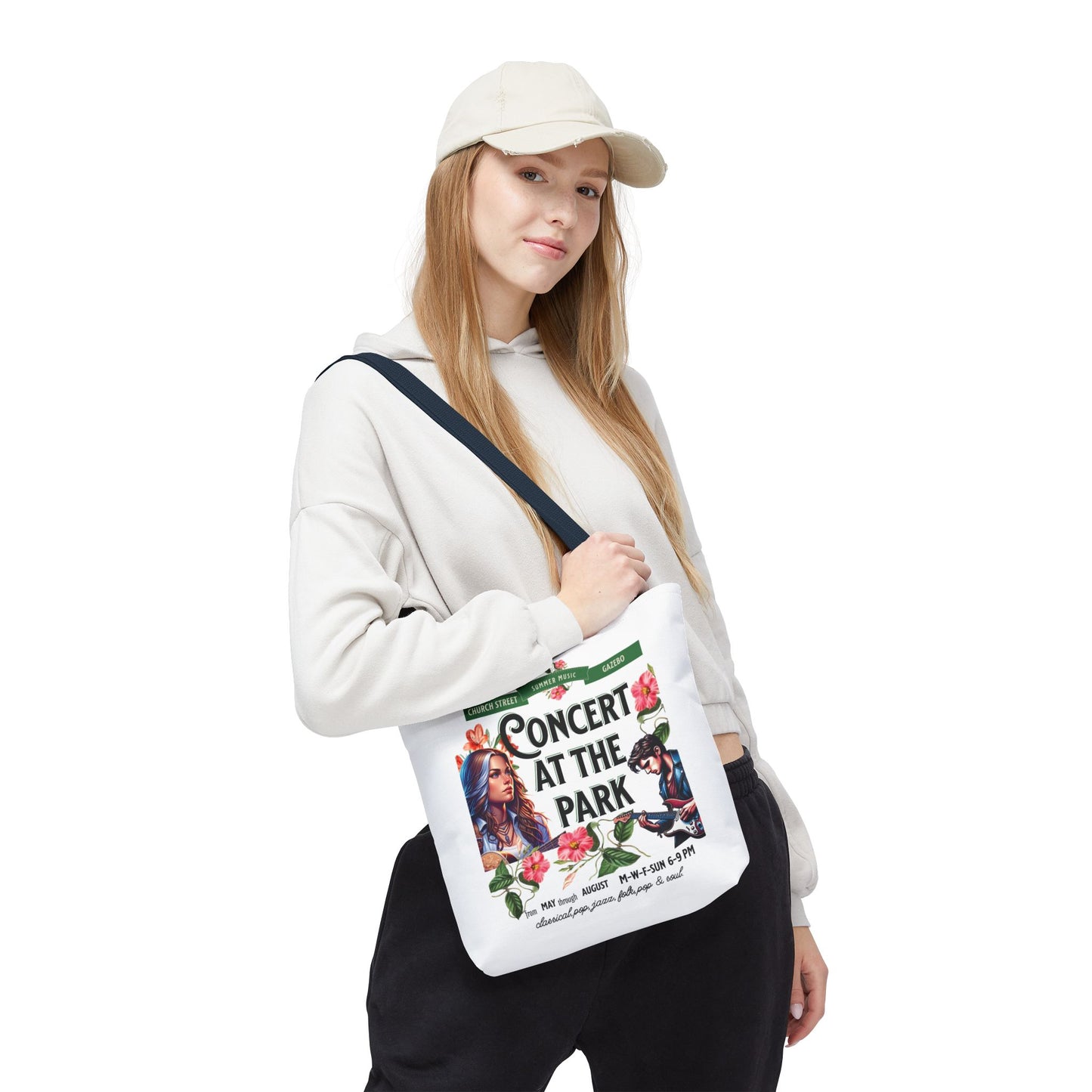 Concert At the Park Tote Bag held by a woman in a white hat and sweatshirt, featuring a lively concert design ideal for outdoor events.