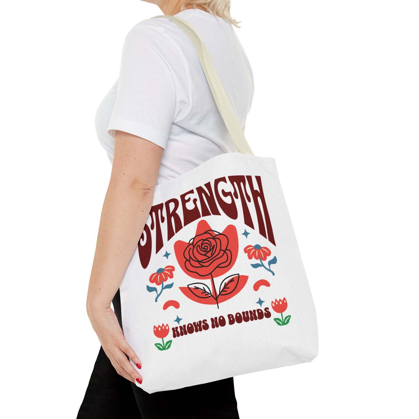 Strength Knows No Bounds Tote Bag with red rose design, held by a woman, showcasing durable handles and spacious interior for everyday use.