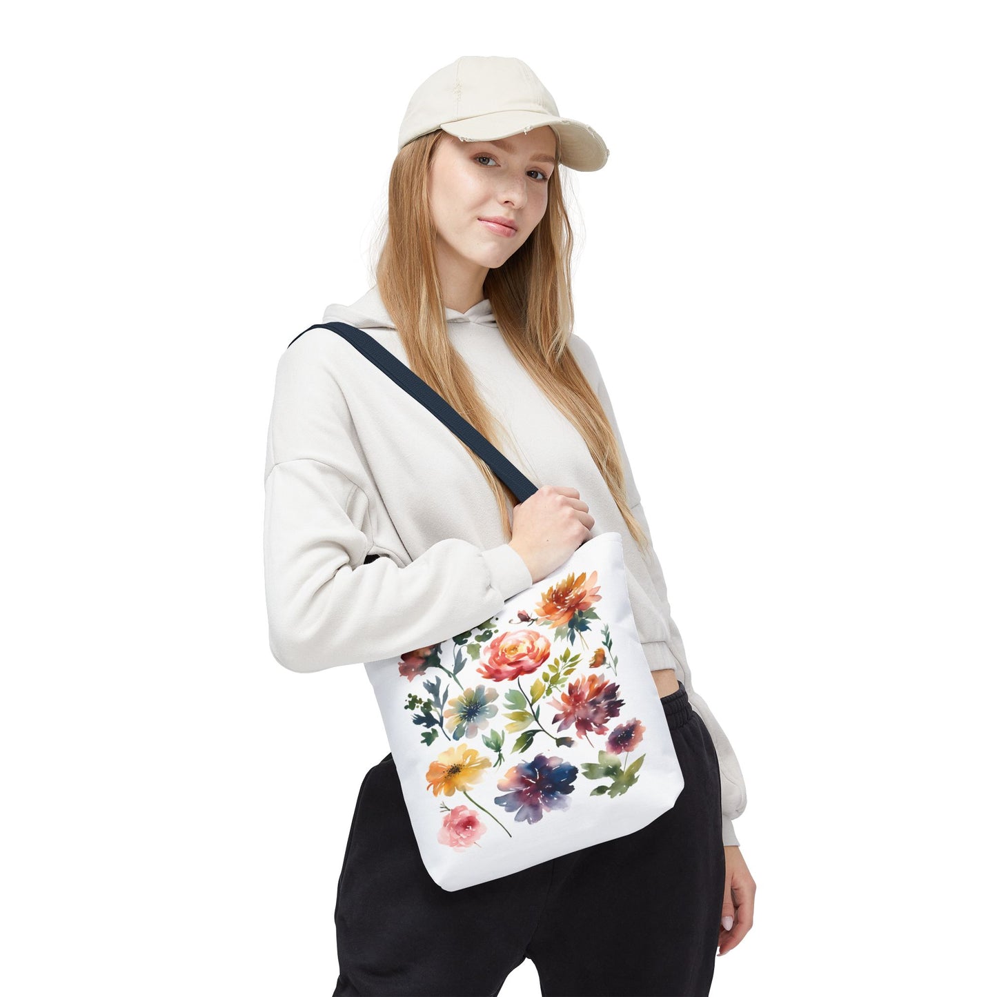 Woman wearing hat and white sweatshirt holds Watercolor Floral Tote Bag, showcasing its artistic design and practical use for shopping or travel.