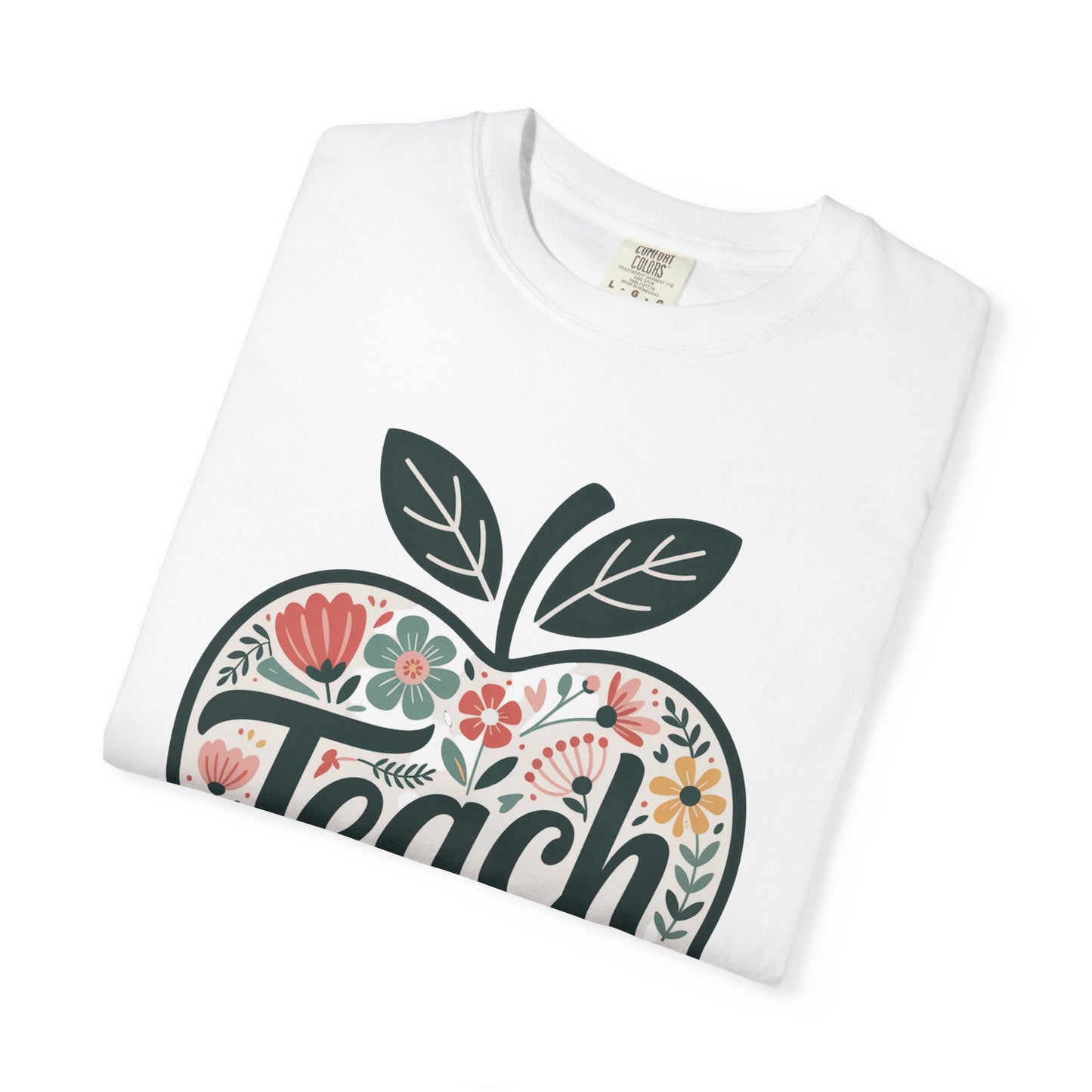 Floral Apple TEACH T-shirt: Unisex garment-dyed tee with a large apple filled with pastel floral illustrations and TEACH in script, perfect for educators. Durable double-needle stitching, soft texture.