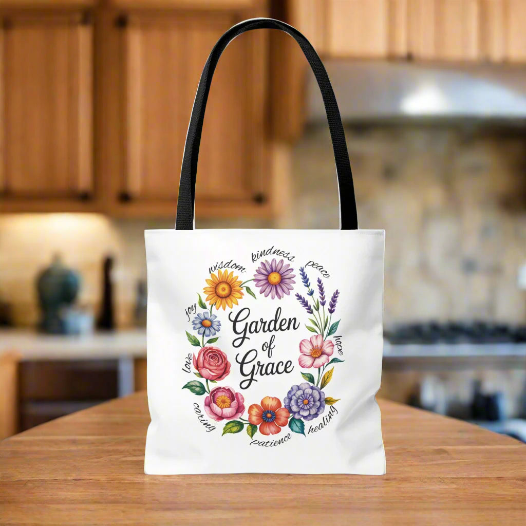 Garden of Grace Watercolor Design Tote Bag features hand-drawn flowers in soft pastels with 'Garden of Grace' text. Durable polyester, reinforced handles, perfect blend of nature-inspired charm and everyday functionality.