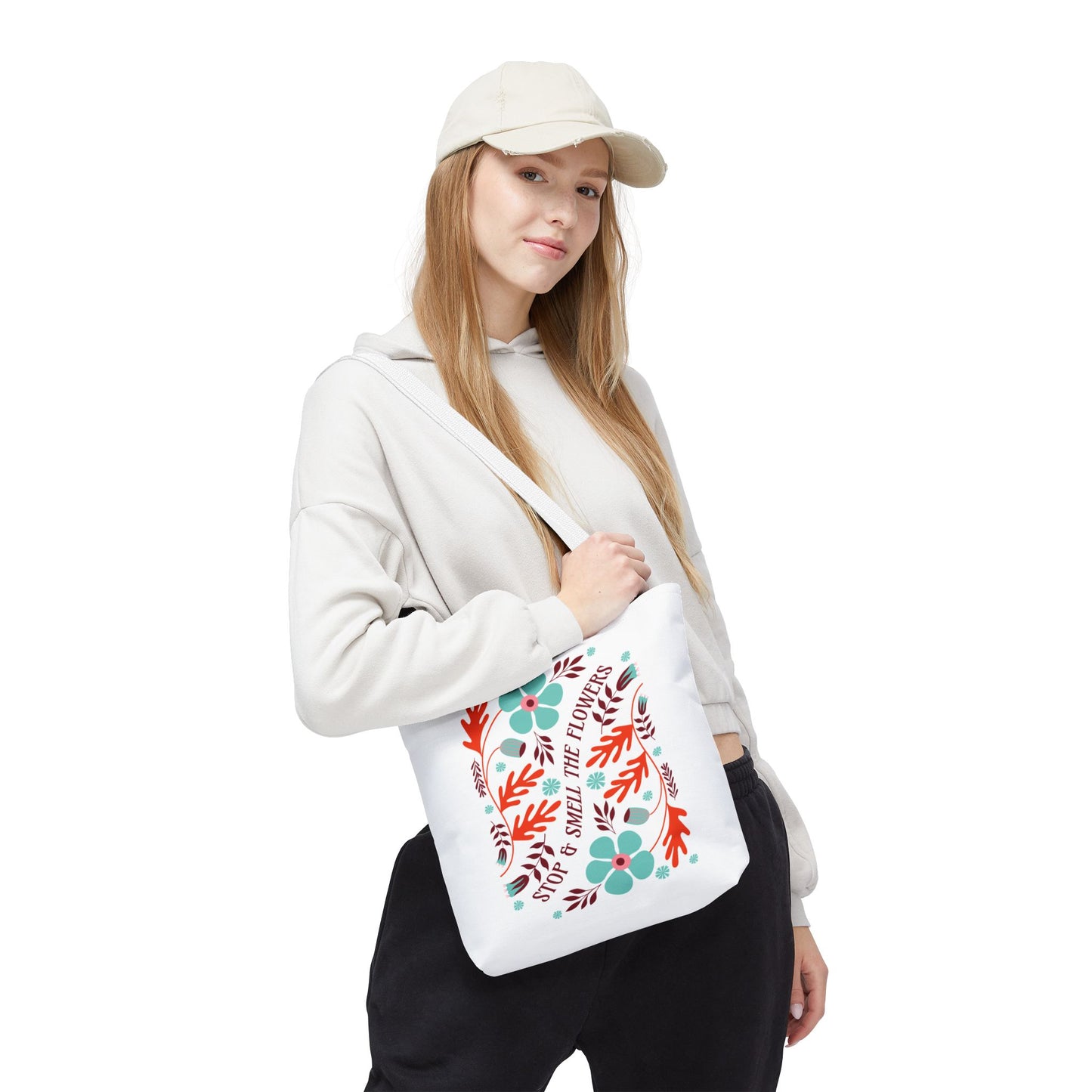 Woman in a hat holding the Stop and Smell The Flowers Tote Bag, showcasing its floral design and spaciousness for everyday essentials.
