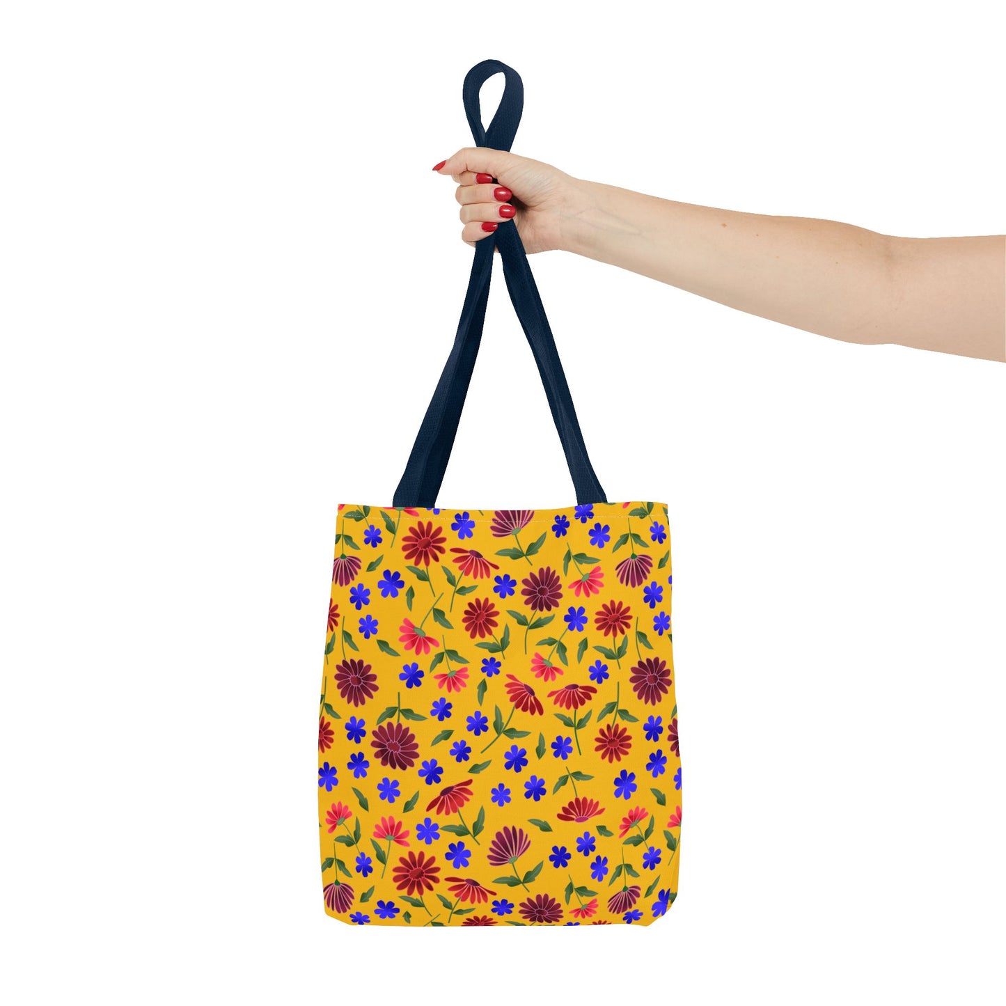 Floral Yellow Tote Bag - Bright Wildflower Pattern held by a hand with red nails, showcasing vibrant blue and red flowers on yellow canvas, black straps; embodies FireBrook Essentials' joyful, stylish design ethos.