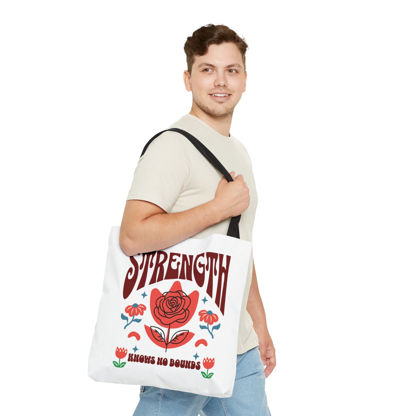 Man smiling, carrying a Strength Knows No Bounds Tote Bag with a red rose design, showcasing its spacious and durable features.