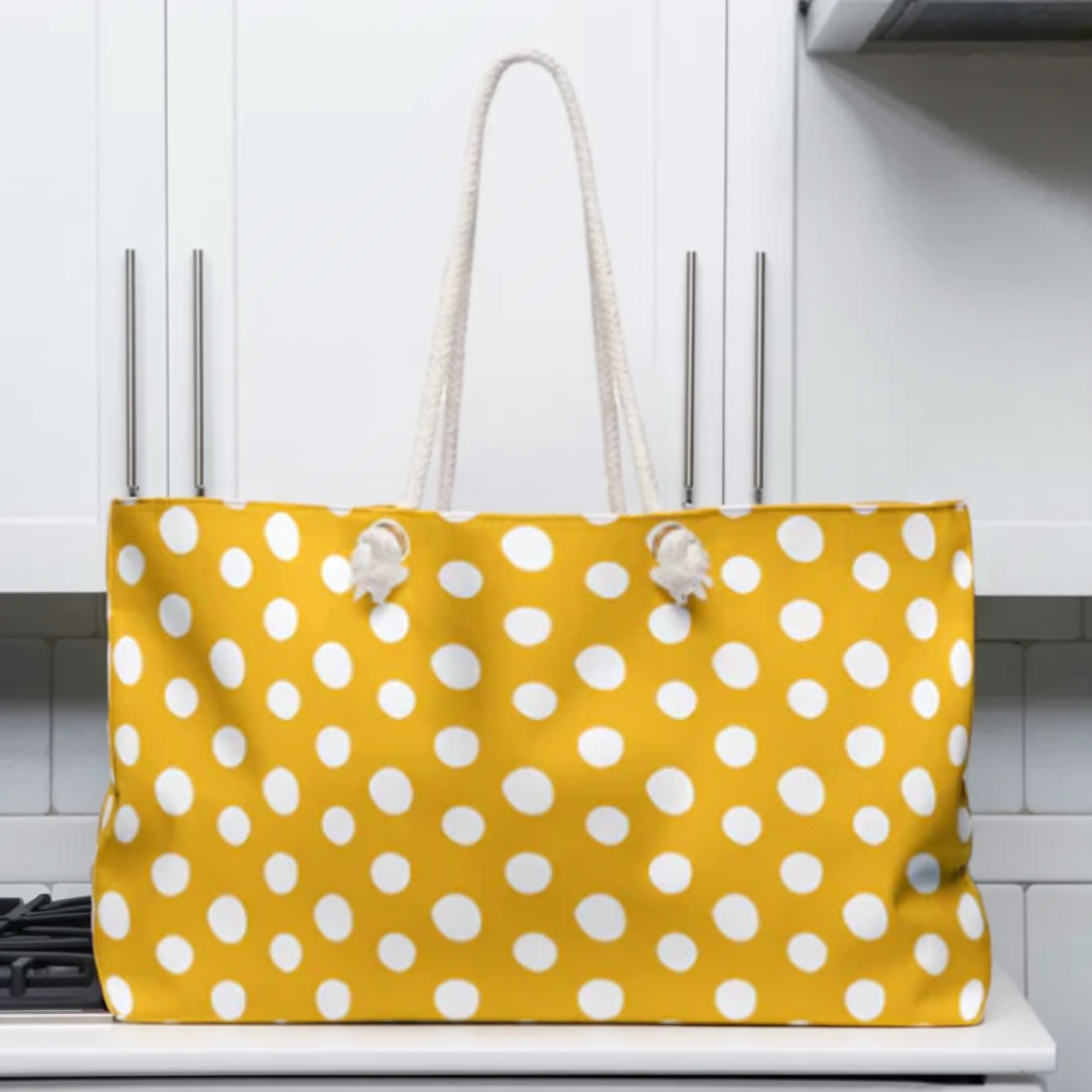 Polka Dot Weekender Bag with yellow and white polka dots, cream rope handles, and gold grommets. Spacious and stylish, ideal for short trips. Perfectly embodies FireBrook Designs' cheerful and practical style.