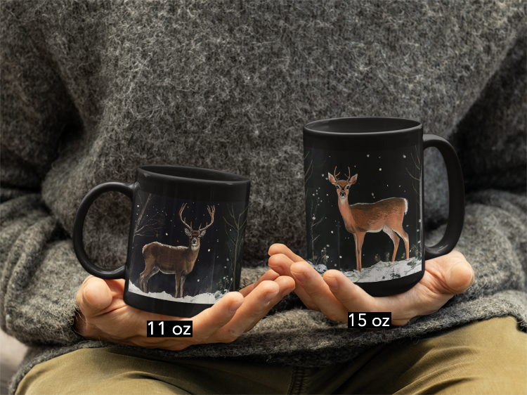 Deer at Snowy Night Mug (11oz, 15oz): A person holds a black ceramic mug showcasing a serene deer in a snowy night design, ideal for cozy moments, reflecting FireBrook Designs' essence of comfort and joy.