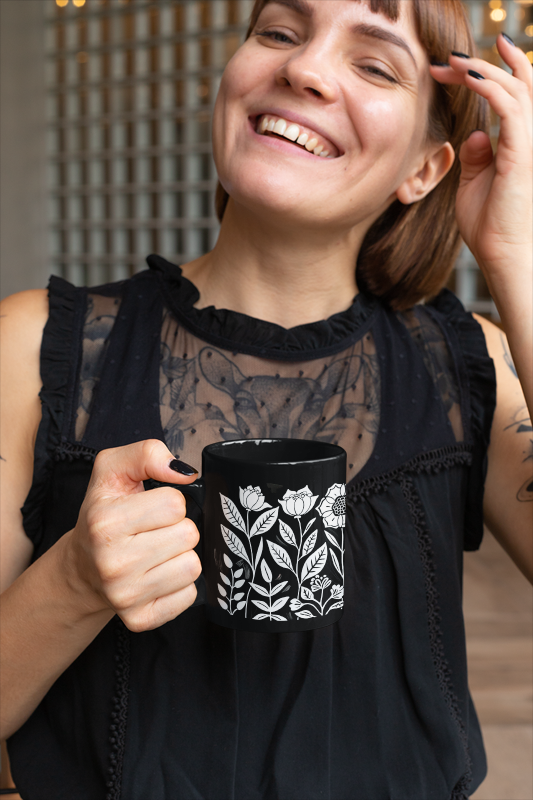 Vintage Flower Mug (11oz, 15oz): A sleek black ceramic mug with a floral design, elegantly held, perfect for cozy mornings. Ideal for minimalist style lovers, crafted by FireBrook Designs for joyful daily use.