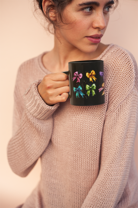 A woman holds a Bows Ribbons Mug (11oz, 15oz) featuring satin ribbons design, showcasing its glossy black ceramic and C-shaped easy-grip handle, ideal for daily use and special occasions.