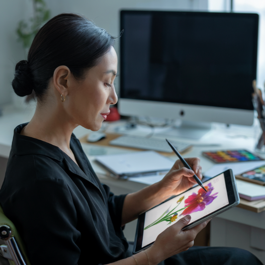A woman interacts with a tablet, while a hand holds a pen nearby, showcasing FireBrook Designs' commitment to blending comfort and style with practical office essentials.