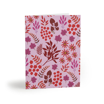 Greeting Cards — Pack of 8/16/24 featuring a lavender-pink background with vibrant floral print, including red blooms and daisylike flowers. Comes with matching white envelopes, ideal for heartfelt messages.