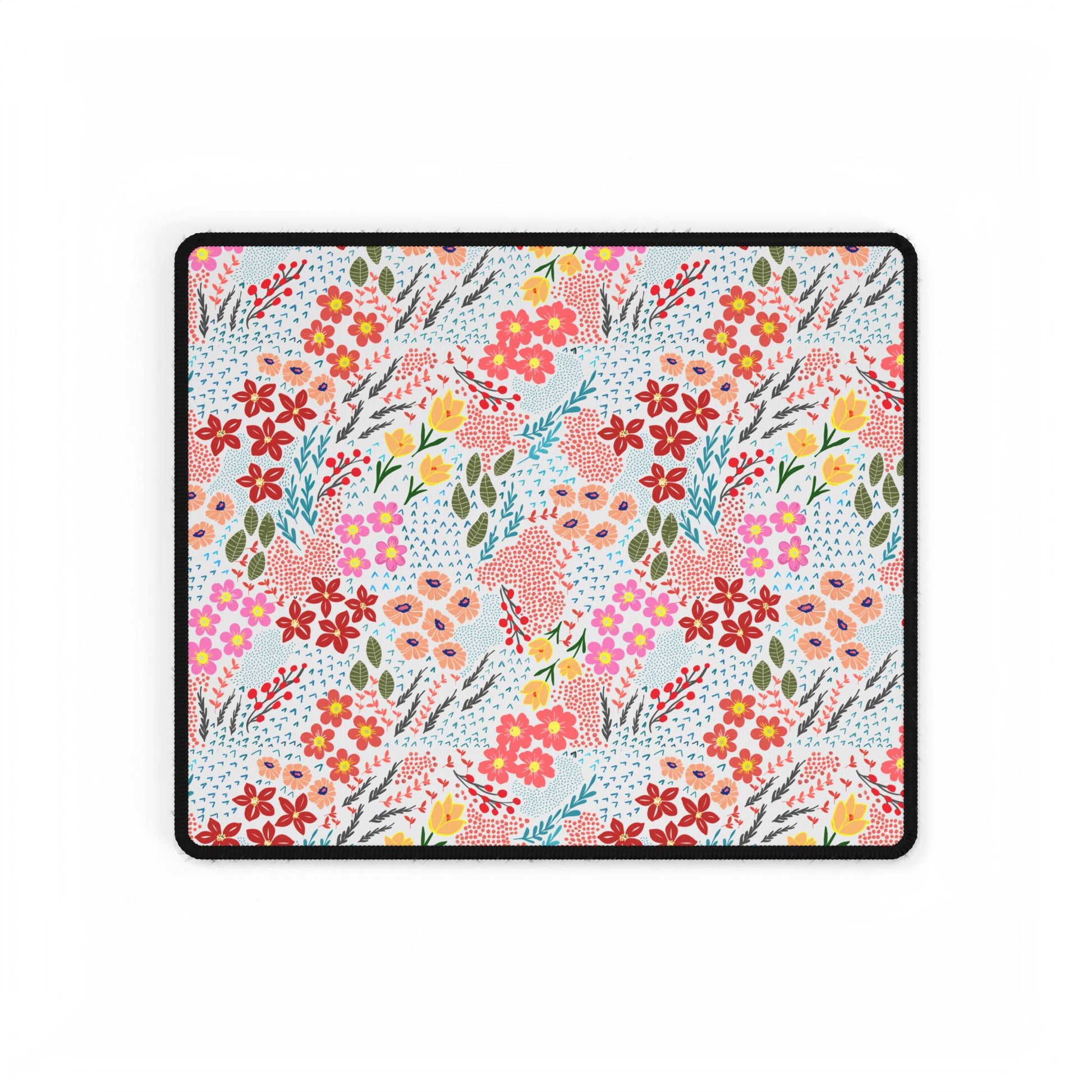 Desk Mats - Garden Floral Pattern features a vibrant floral design with red, pink, peach, and yellow blossoms on a white background, bordered in black stitching, enhancing your workspace with elegance.
