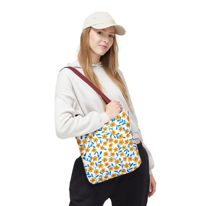 Young woman carrying the Floral Tote Bag, featuring small yellow-orange flowers and blue leaves on a white background with a red strap, perfect for summer outings. Ideal for adding cheerful style to any casual look.