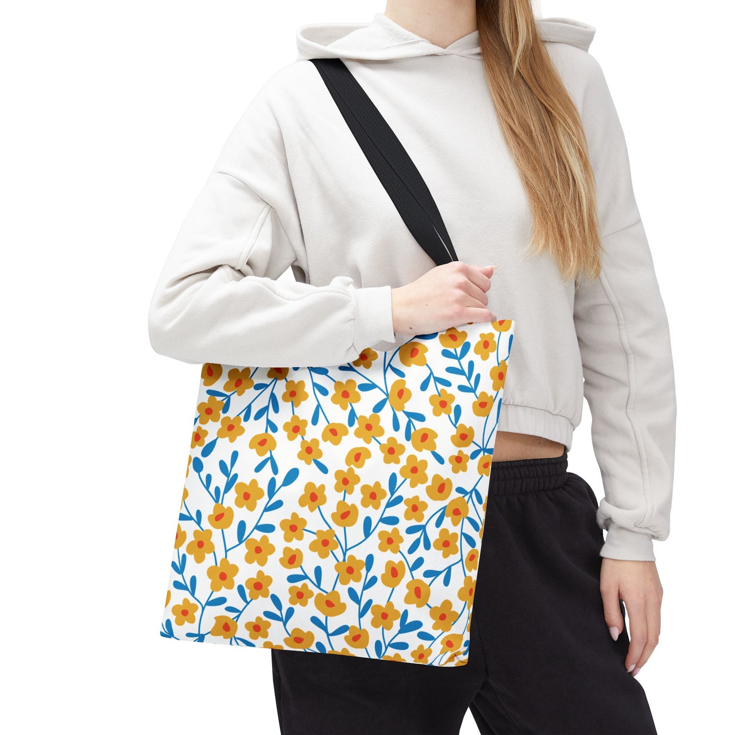 Floral Tote Bag with yellow flowers and blue stems, held by black strap. Perfect for summer outings, this stylish accessory embodies FireBrook Essentials' cheerful and uplifting design ethos.