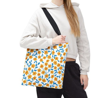 Floral Tote Bag with yellow flowers and blue stems, held by black strap. Perfect for summer outings, this stylish accessory embodies FireBrook Essentials' cheerful and uplifting design ethos.