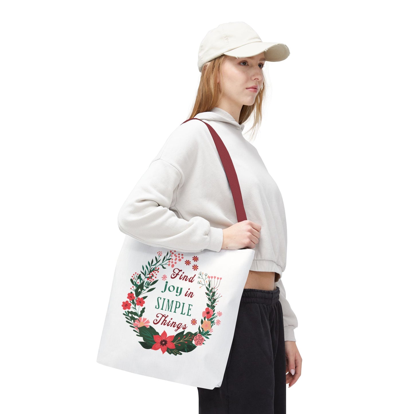 Woman in white hat holding the Find Joy in Simple Things tote bag with a floral design, highlighting its stylish and practical features.