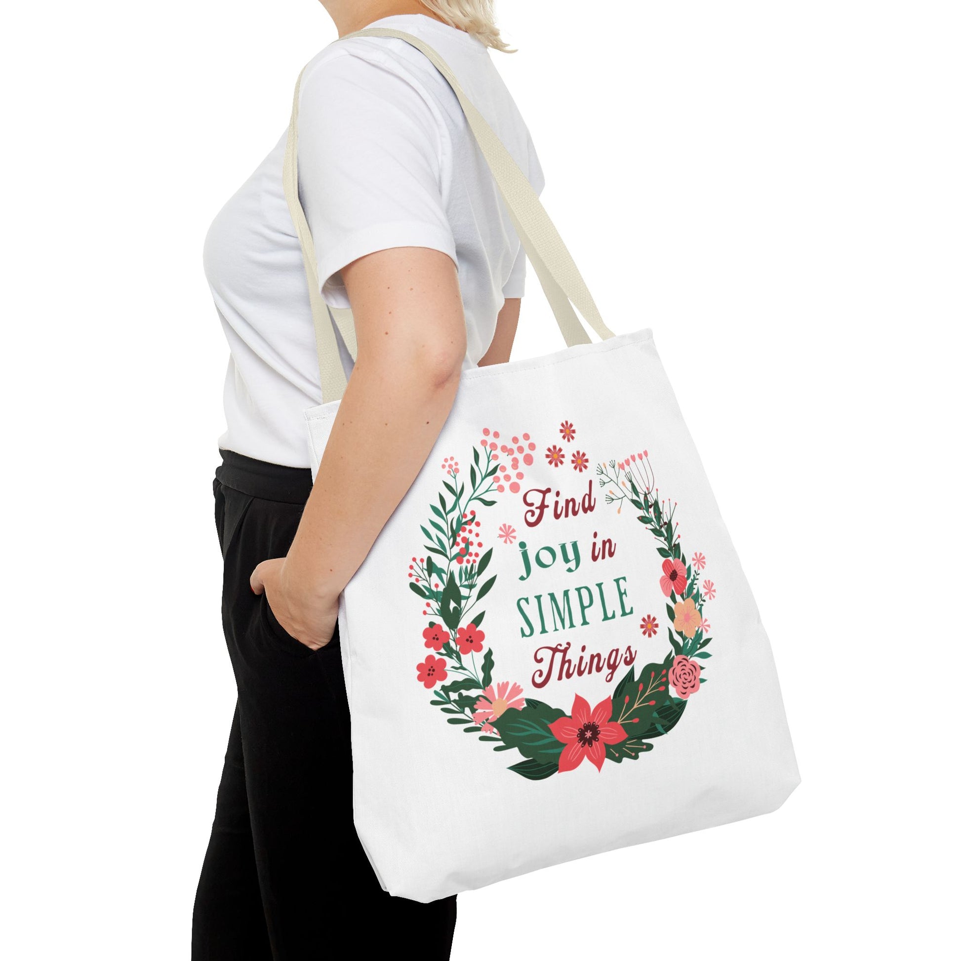 A woman holds the Find Joy in Simple Things tote bag, featuring a watercolor floral design, ideal for stylish, practical carrying needs.