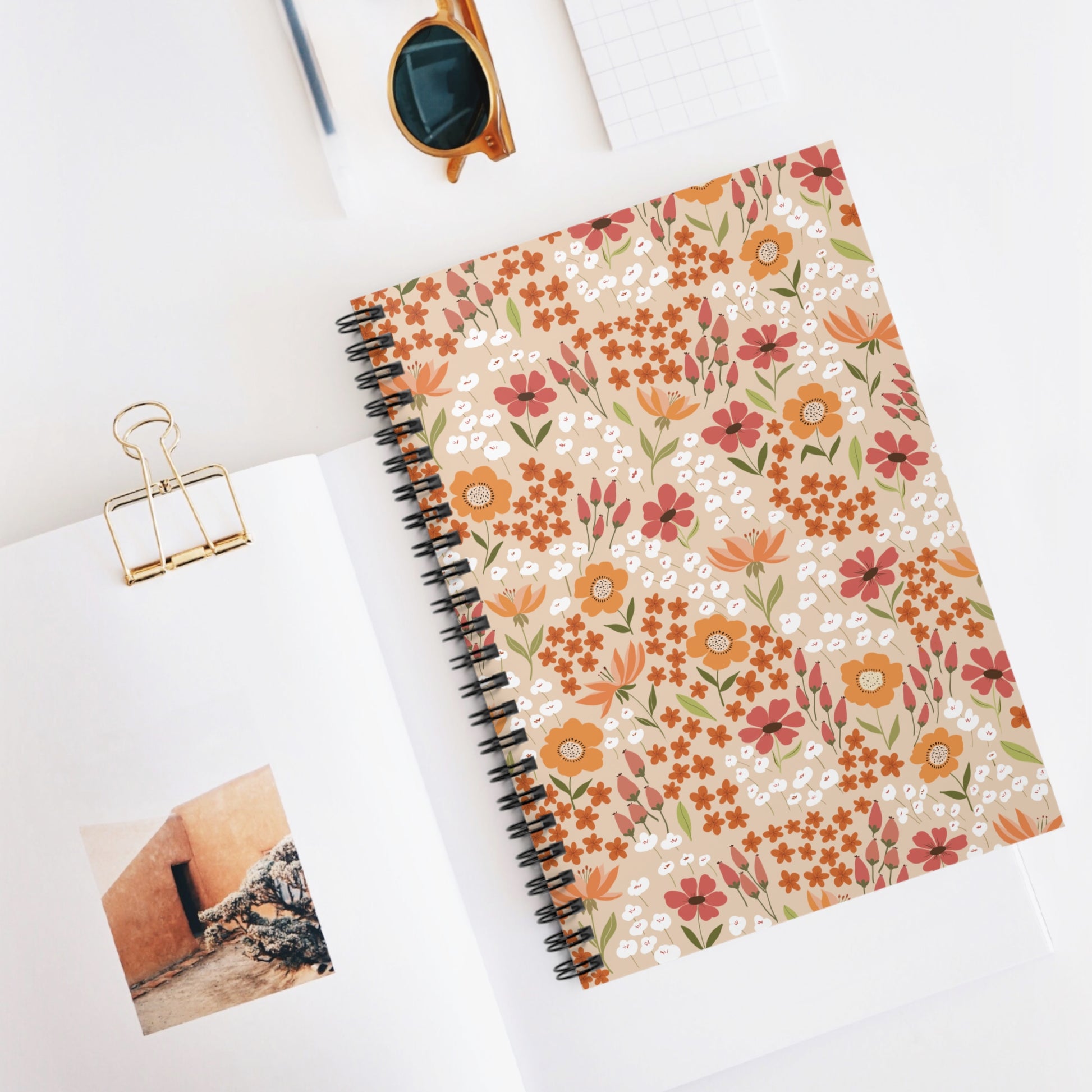 Floral Spiral Notebook with a vibrant ditsy floral cover, central in a tidy desktop setup, emphasizing creativity and organization. Perfect for jotting notes or sketching, reflecting FireBrook Designs' joyful essence.