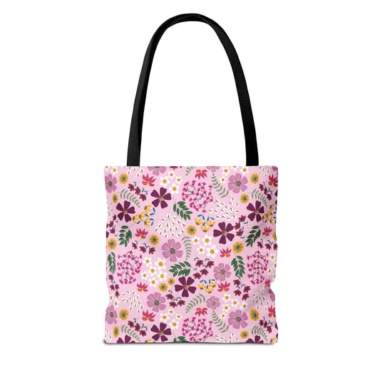 Rose Garden Blush Tote Bag featuring a vibrant floral pattern on a light pink background with black shoulder straps, ideal for everyday use with durable polyester and reinforced stitching for longevity.