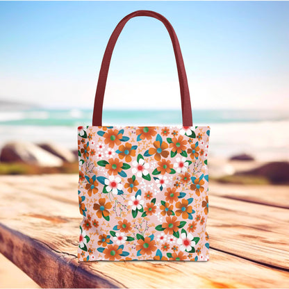 Peach Poppy Grove Tote Bag on a wooden surface, showcasing a vibrant floral design with orange, white, and teal blossoms. Features burgundy handles, embodying FireBrook Essentials' joyful, stylish essence.