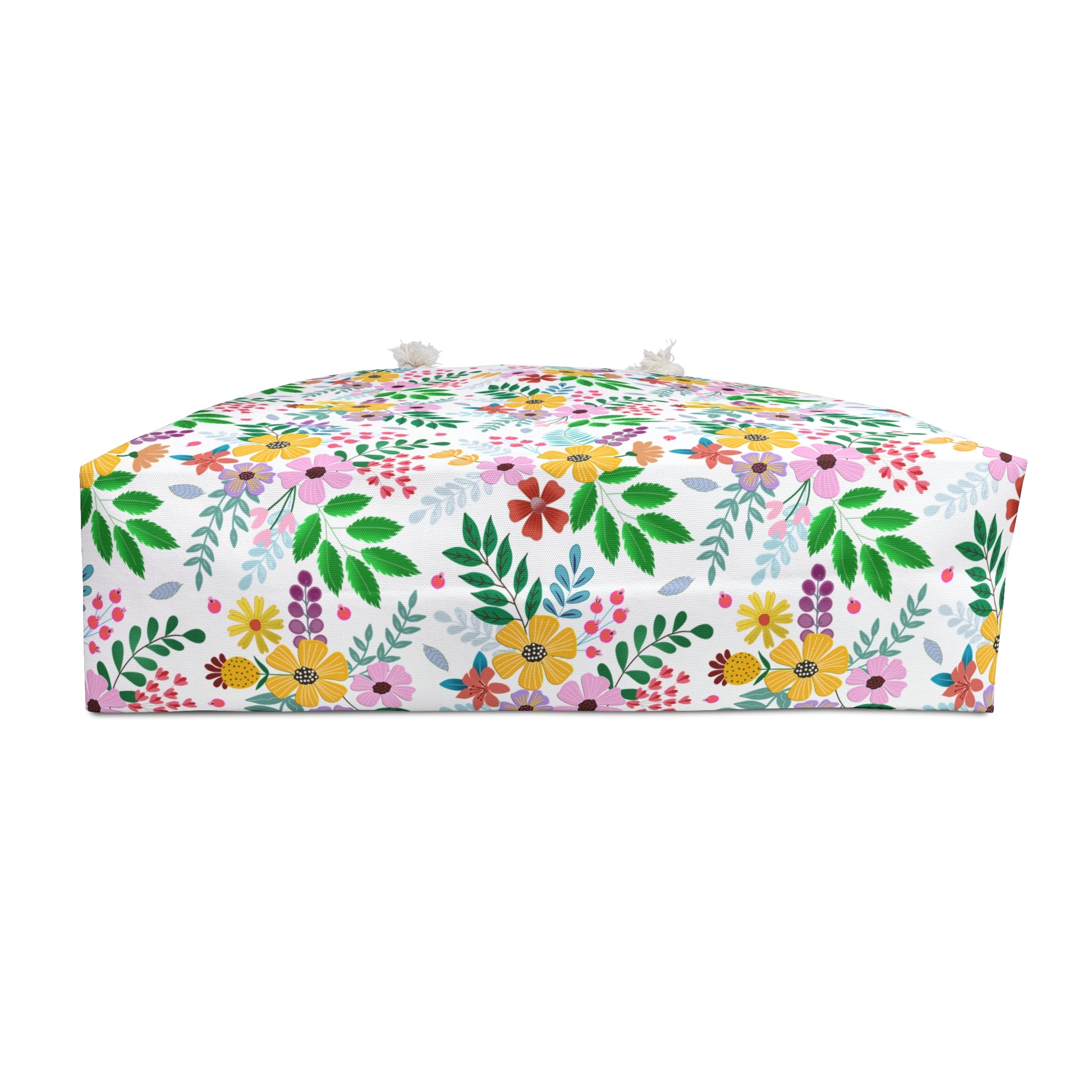 Weekender Bag: A low, box-shaped floor pouf with a vibrant floral and leaf pattern, featuring tassel-style knots on top corners, embodies FireBrook Essentials' commitment to stylish, joyful designs.