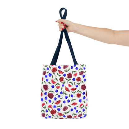 Floral Pattern Tote Bag — Red & Blue Wildflower All-Over Print held by a hand with red nails, showcasing its white canvas body adorned with vibrant floral patterns and navy handles, embodying cheerful, practical elegance.