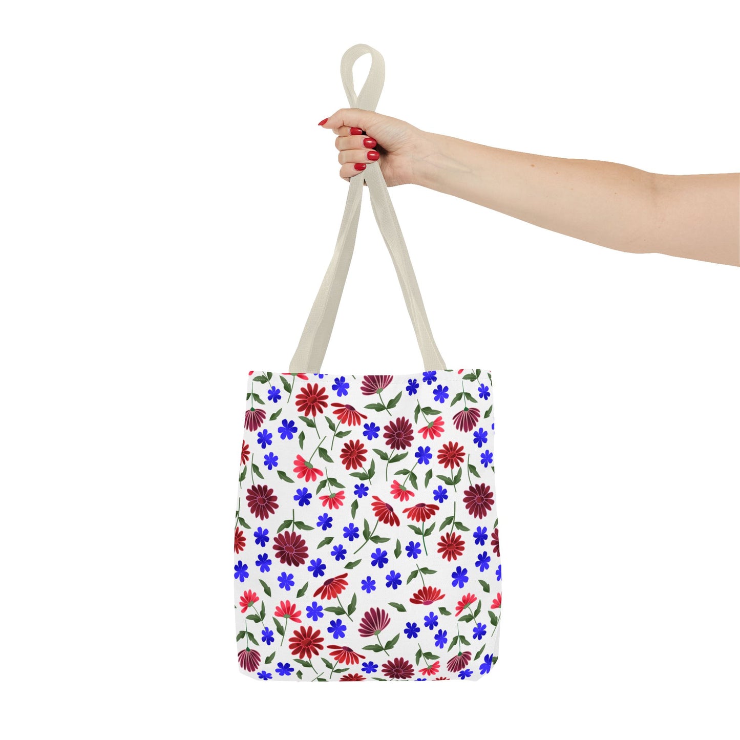 Floral Pattern Tote Bag — Red & Blue Wildflower All-Over Print held by a person with red nails. Showcases vibrant floral design with green leaves, black handles, and roomy corners, embodying FireBrook Essentials' joyful style.
